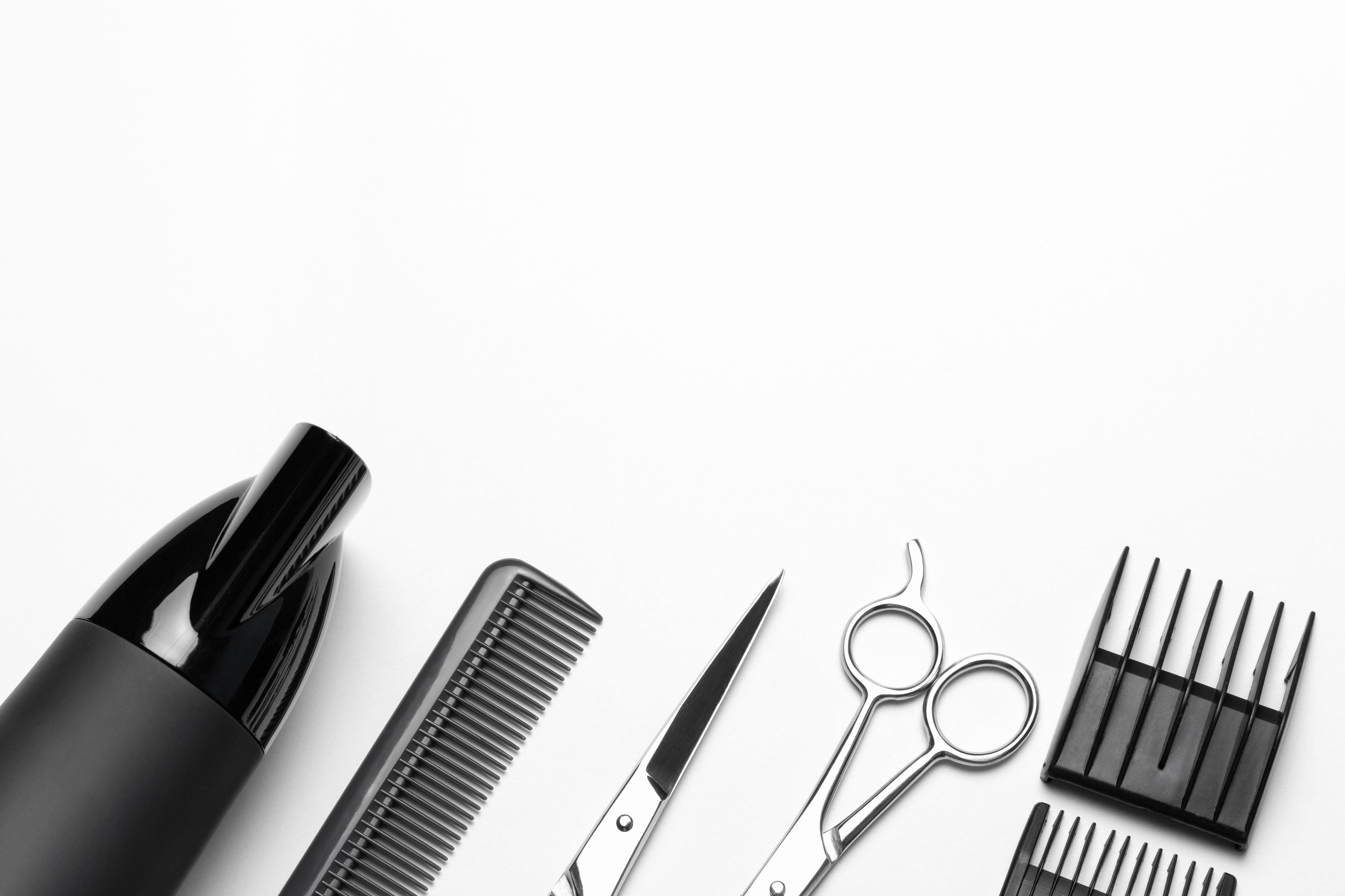 Un ensemble d’outils pour le coiffeur, sèche-cheveux, ciseaux, peigne, sur fond blanc, vue supérieure, une copie de l’espace