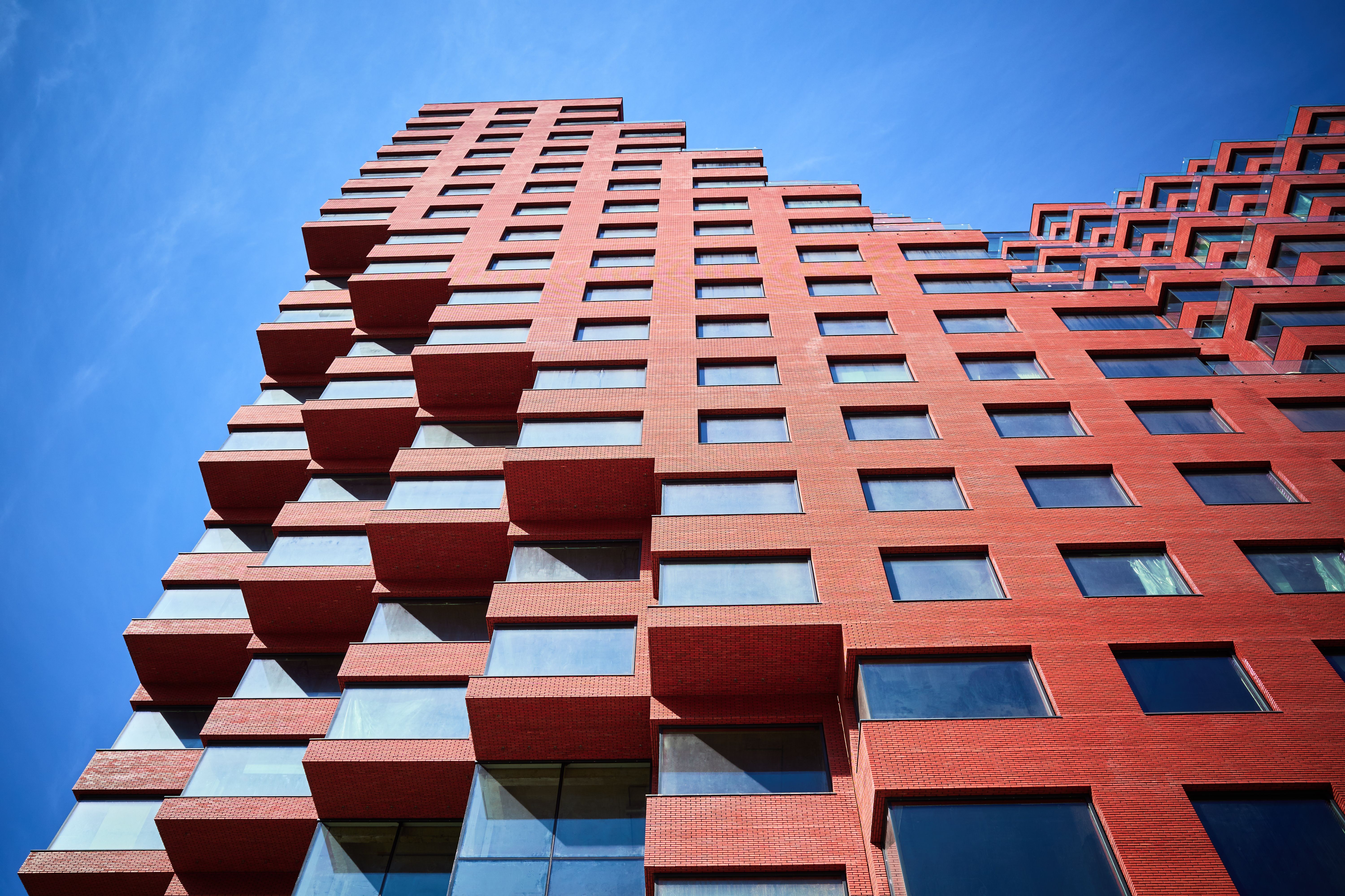 Part of a new multi-story red office building under construction from below
