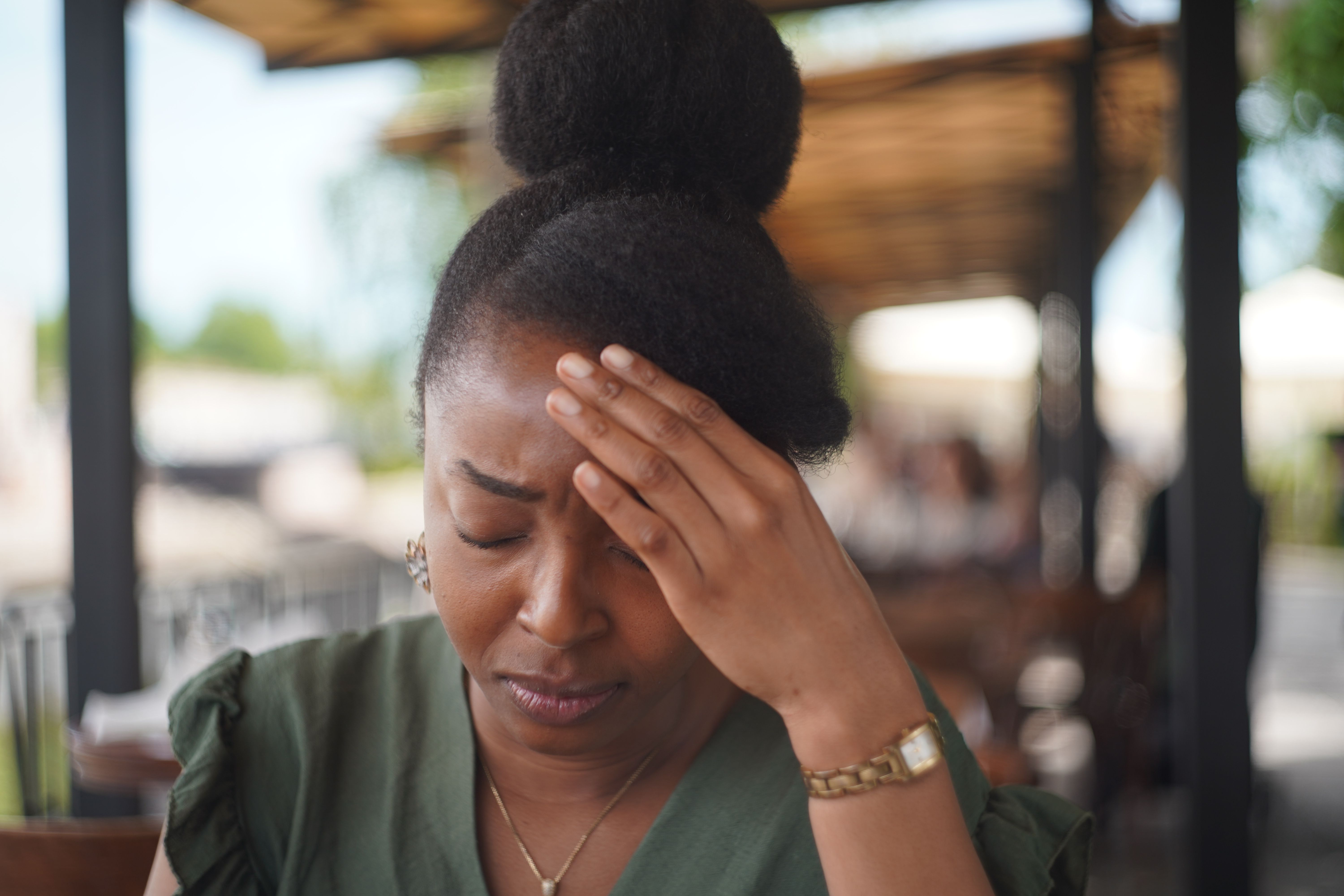Young woman worried or with a headache or with stress sitting in a cafe outdoor Young woman worried or with a headache or with stress sitting in a cafe outdoor