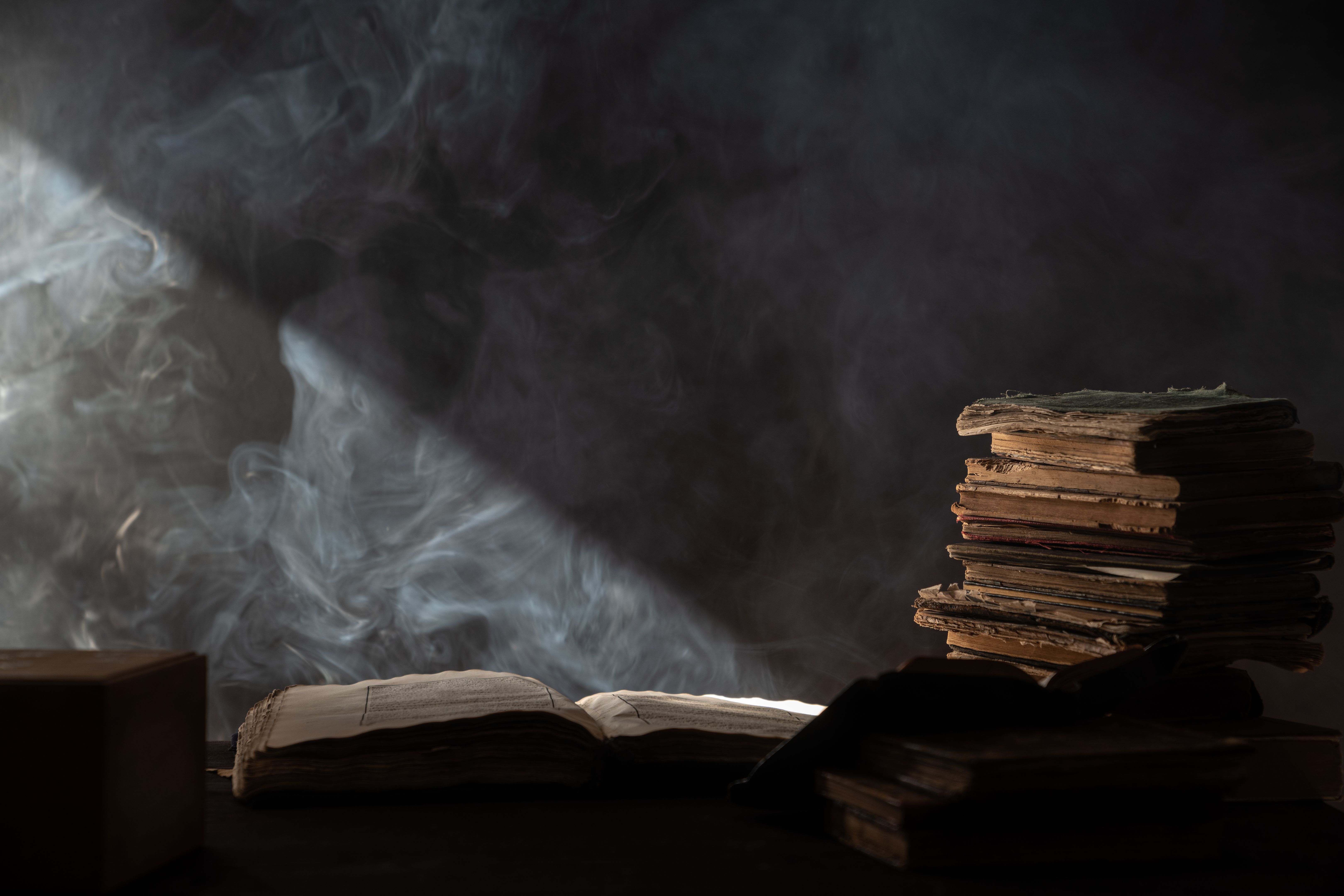 Big Antique Book On Top Of Stack Of books In Dark