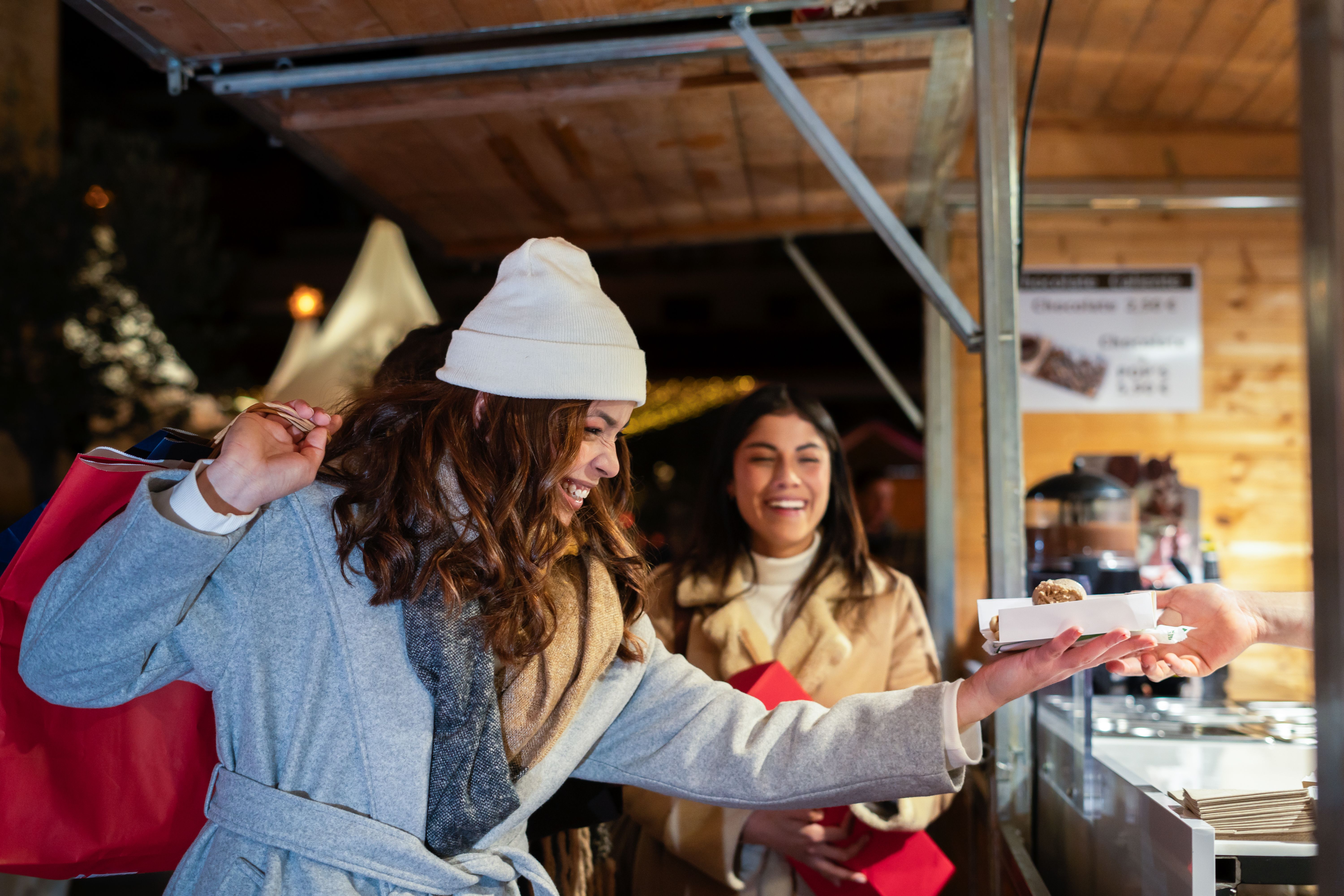 Friends buying snacks at christmas market stall Friends buying snacks at christmas market stall