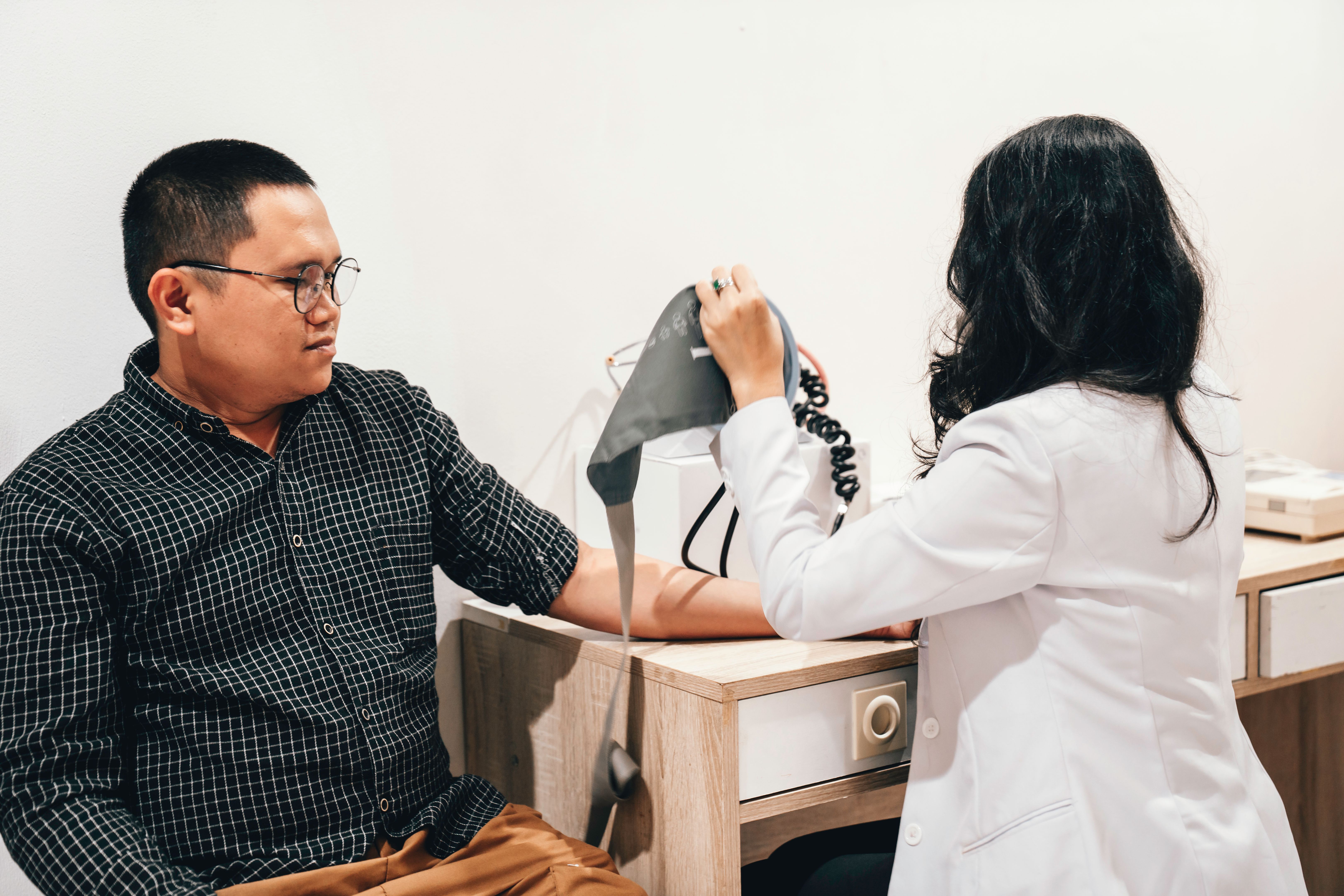 Female Doctor taking a man's blood pressure reading Female Doctor taking a man's blood pressure reading