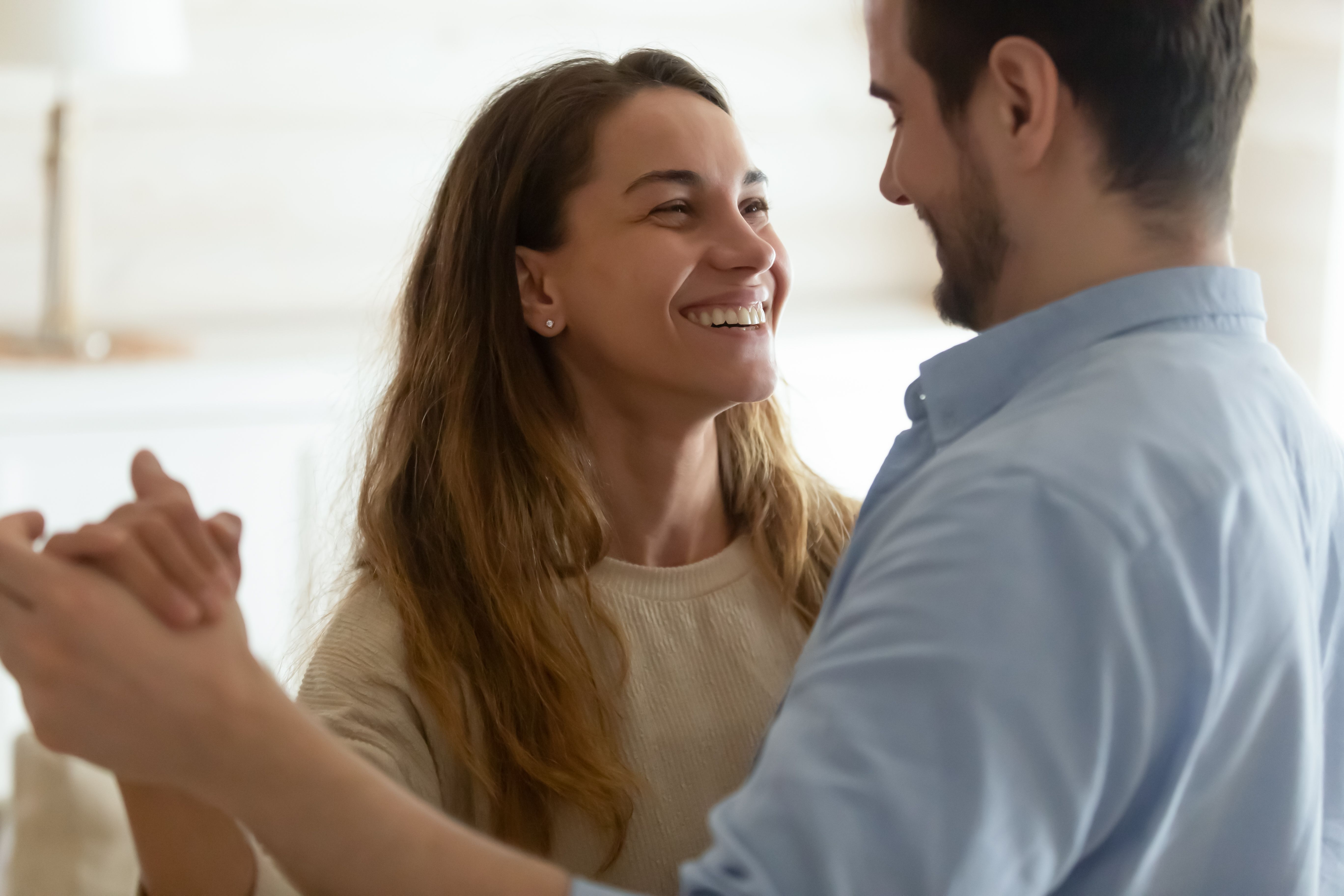 Happy young couple dance at home celebrating