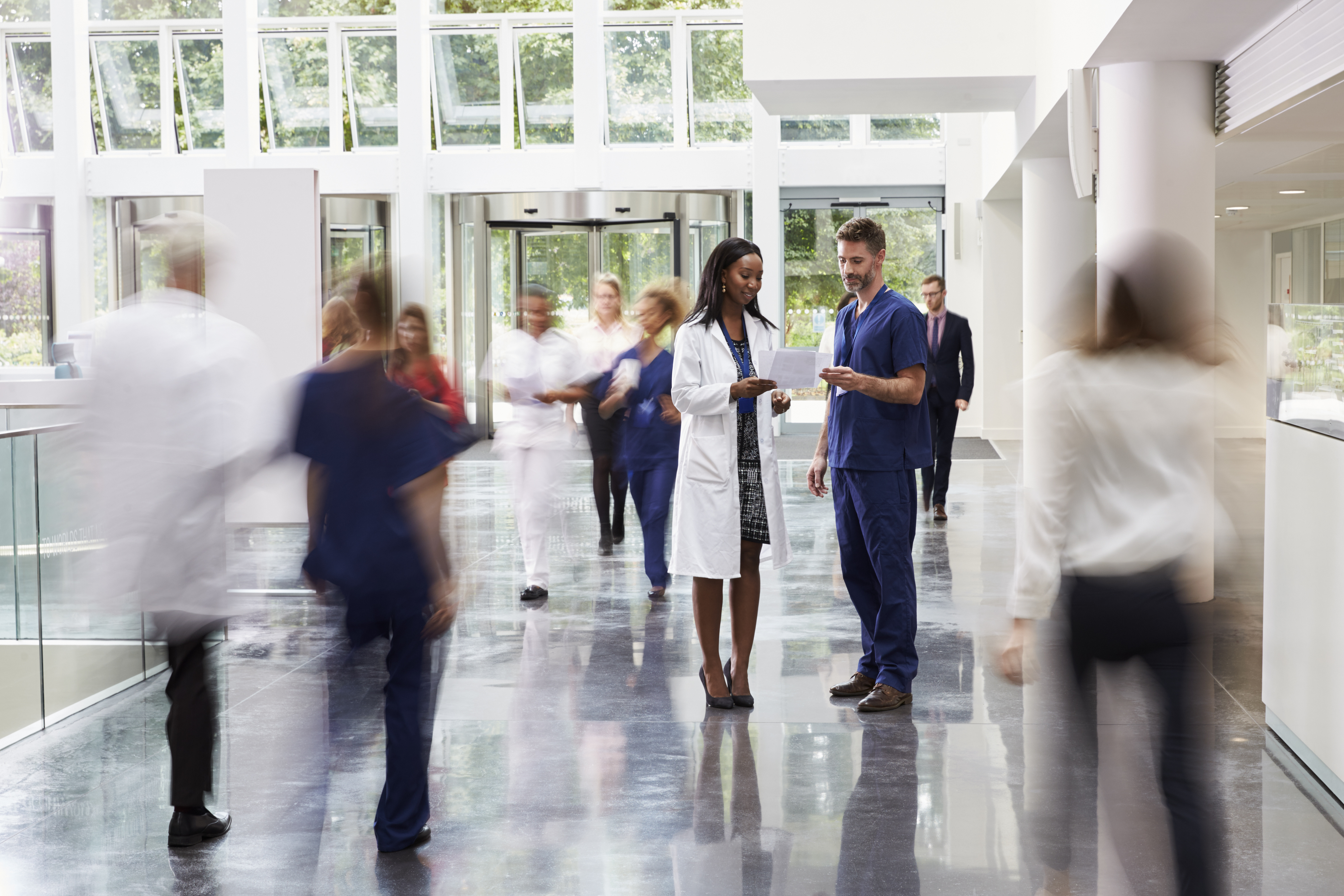 Staff In Busy Lobby Area Of Modern Hospital Staff In Busy Lobby Area Of Modern Hospital