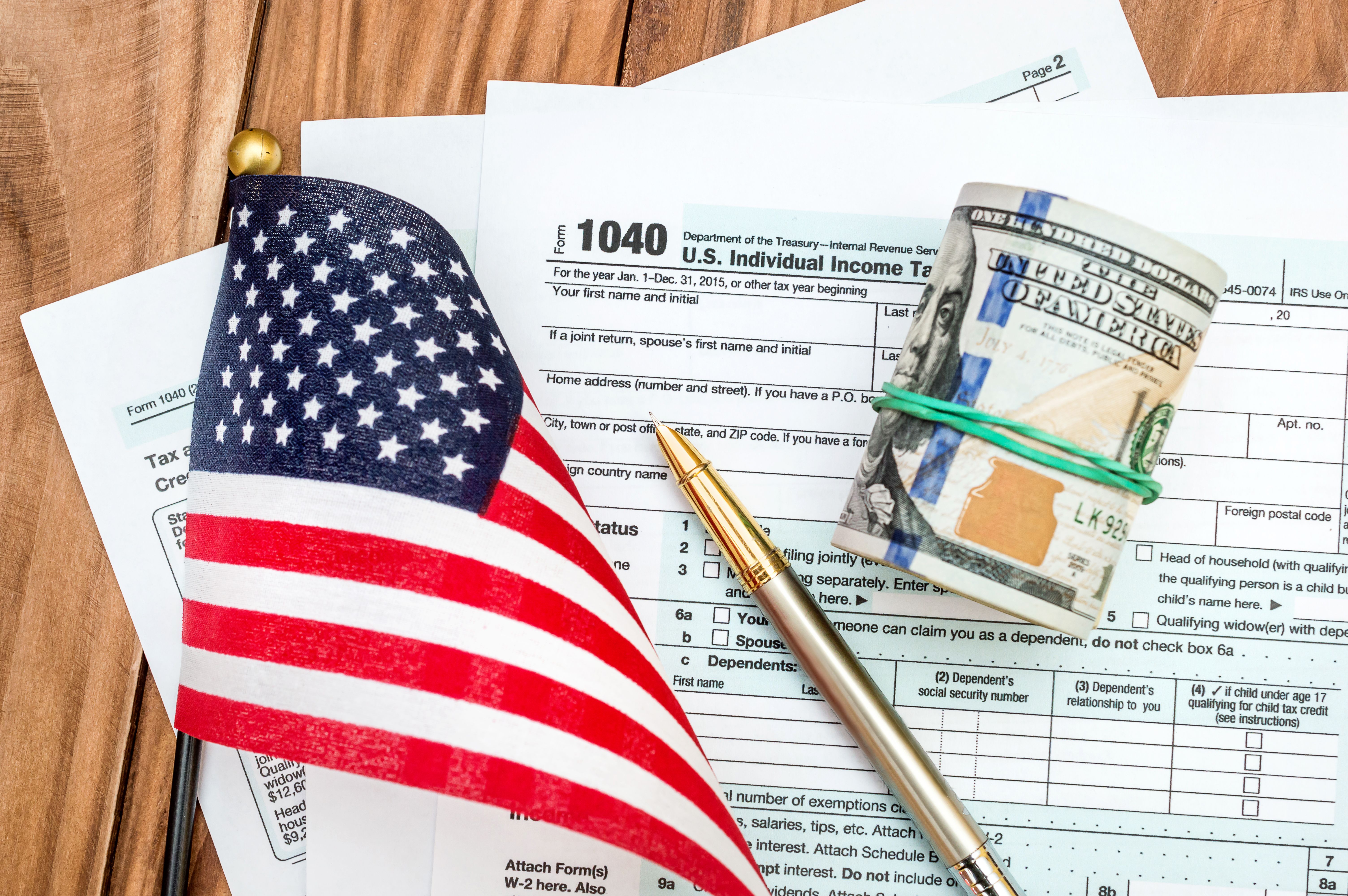 Tac concept. Tax form with small american flag and dollar bills on the table.