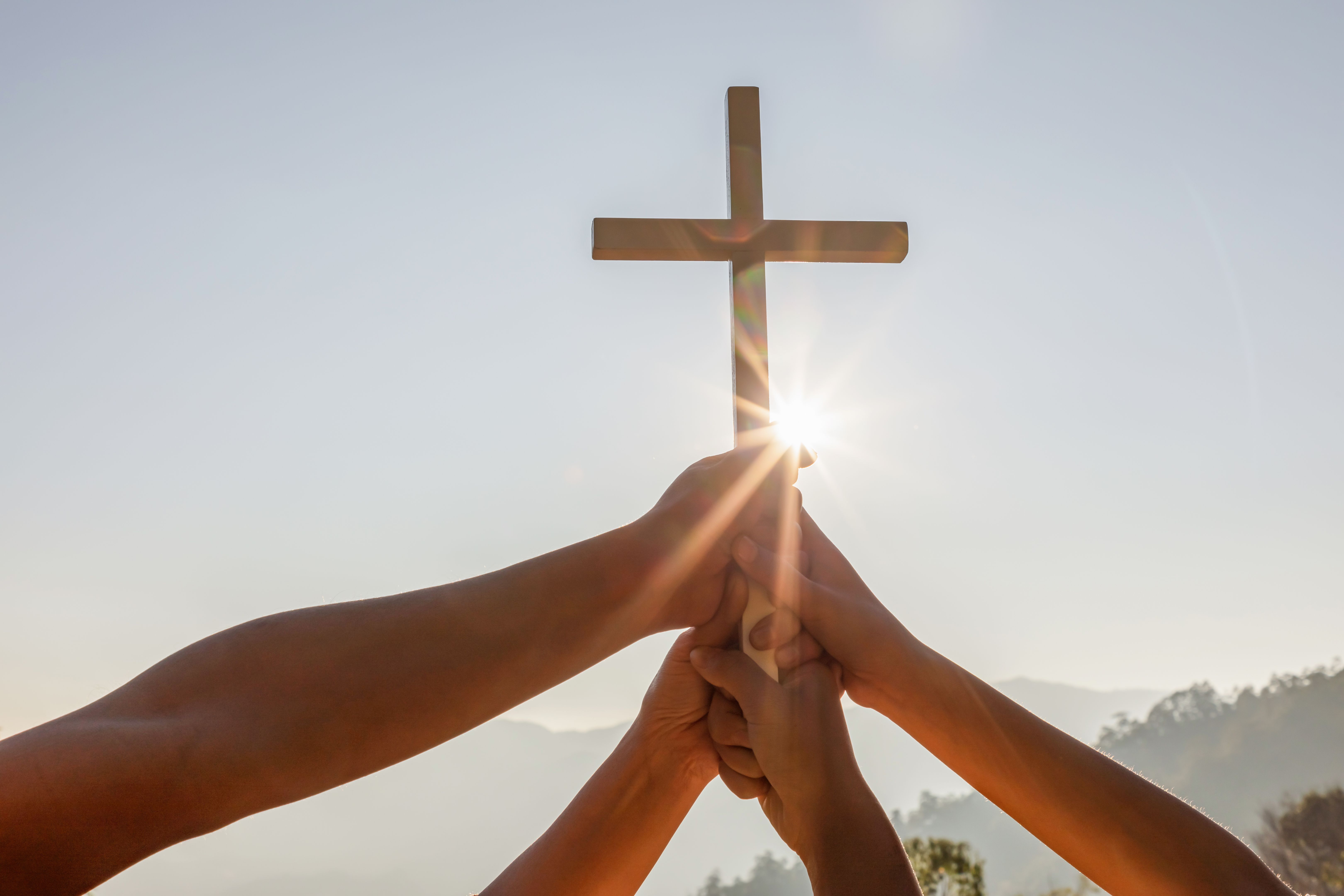 Christian, Christianity, Religion copy space background. Group hands praying and holding christian cross for worshipping God at sunset background.silhouette