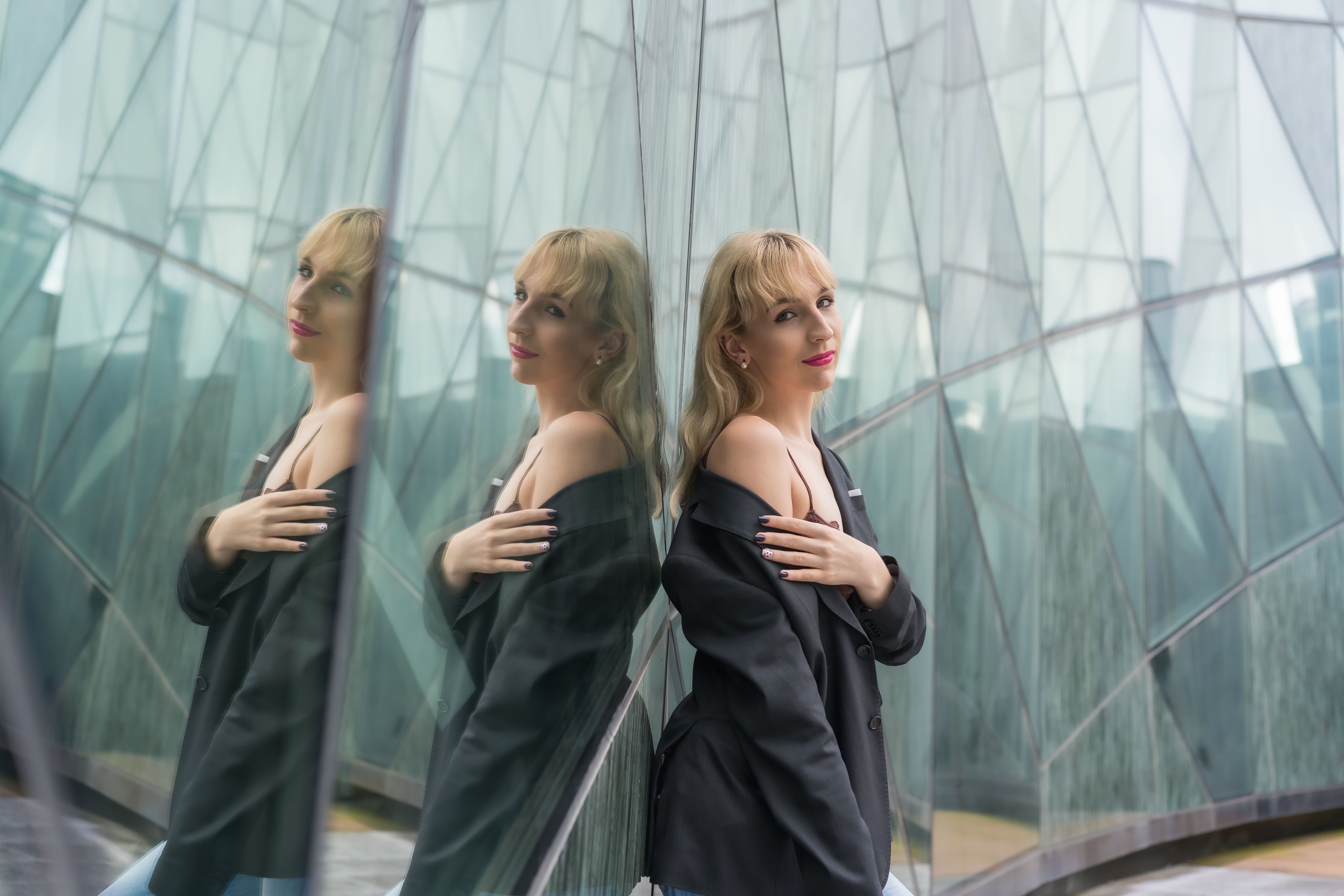 Attractive sexy Caucasian woman in suit reflected against a modern glass building Attractive sexy Caucasian woman in suit reflected against a modern glass building