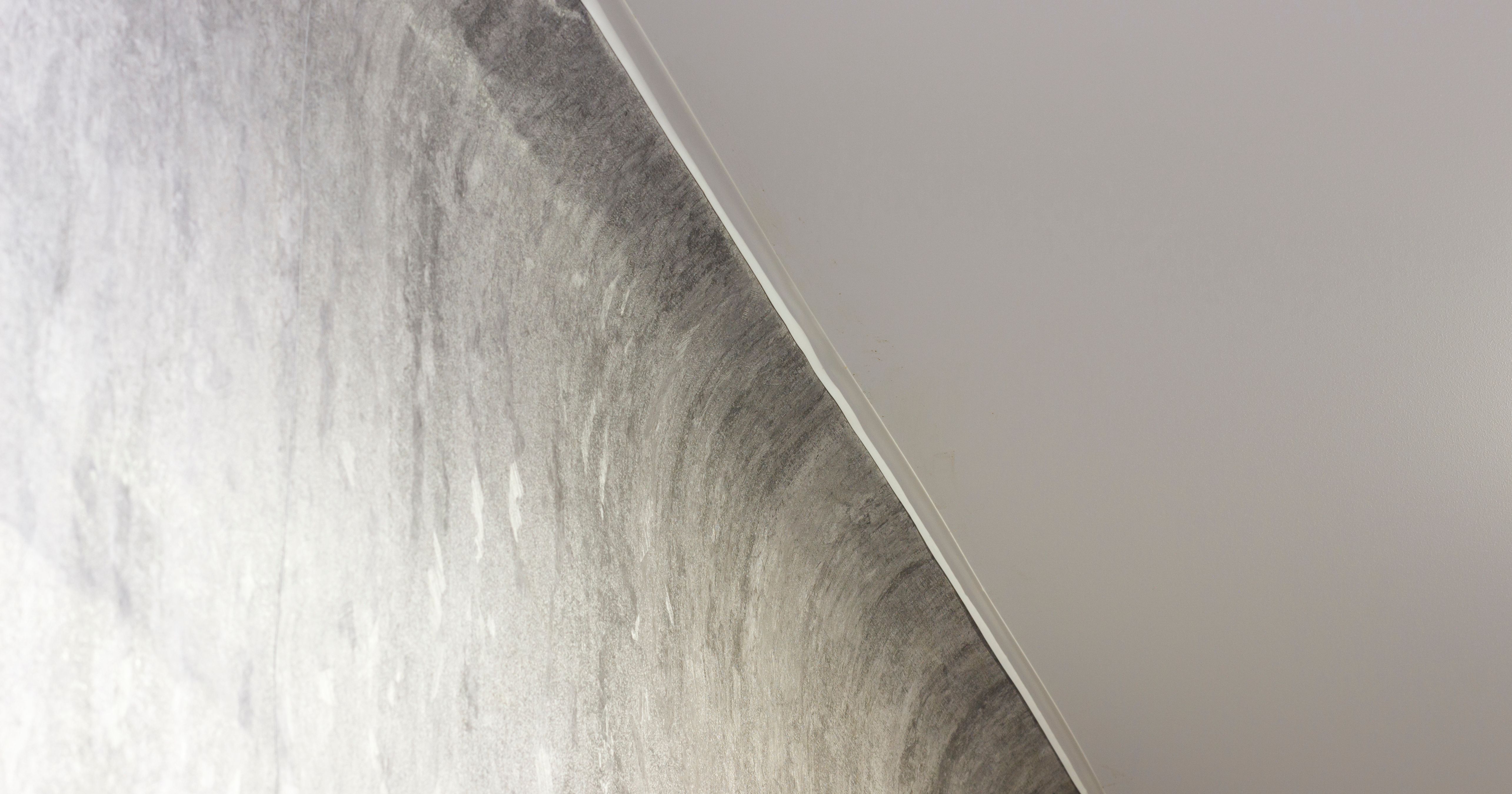 Textured wall meets ceiling at an angle, featuring modern, minimalist interior design with soft lighting.