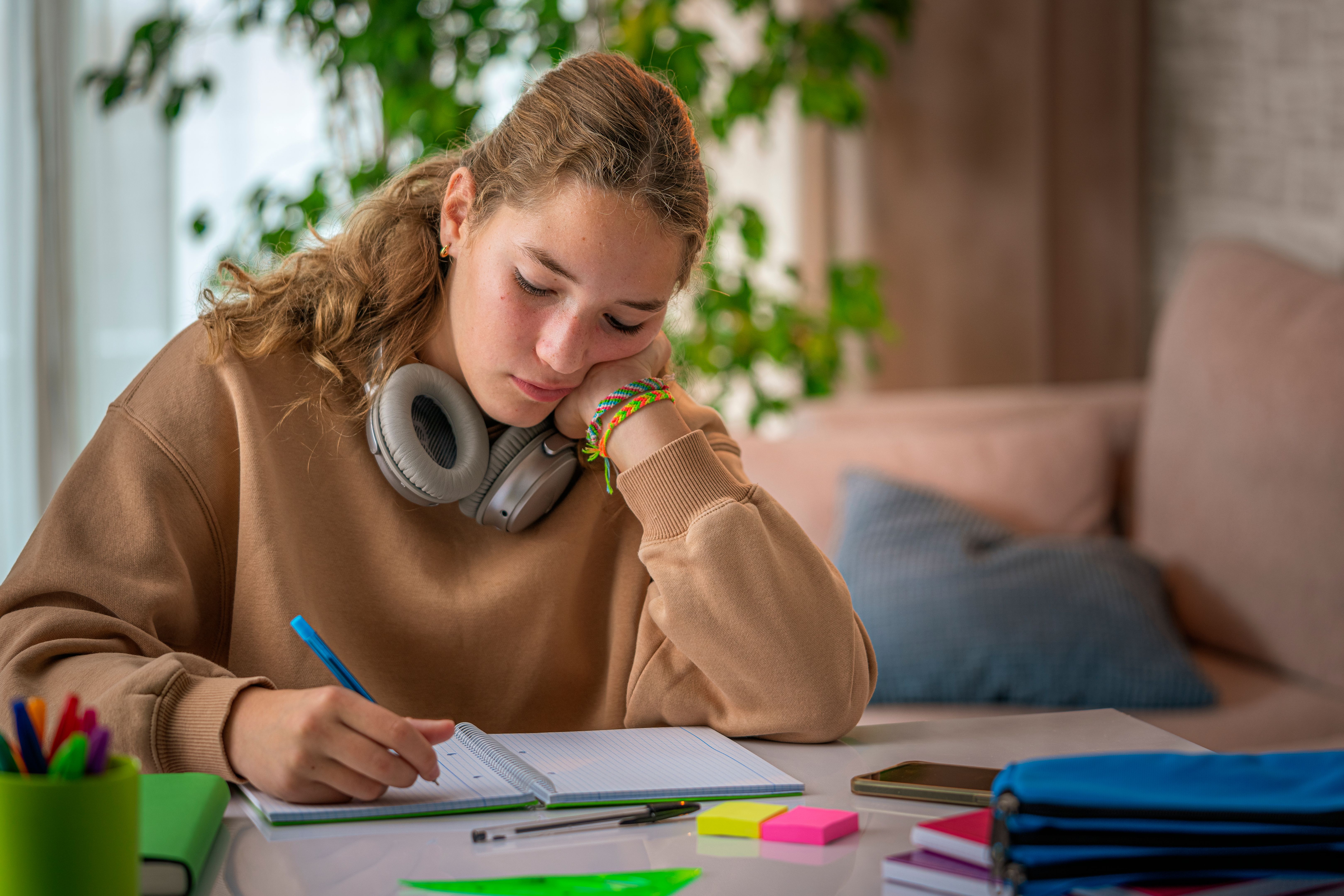Teen girl bored and unhappy while doing a school assignment at home Teen girl bored and unhappy while doing a school assignment at home