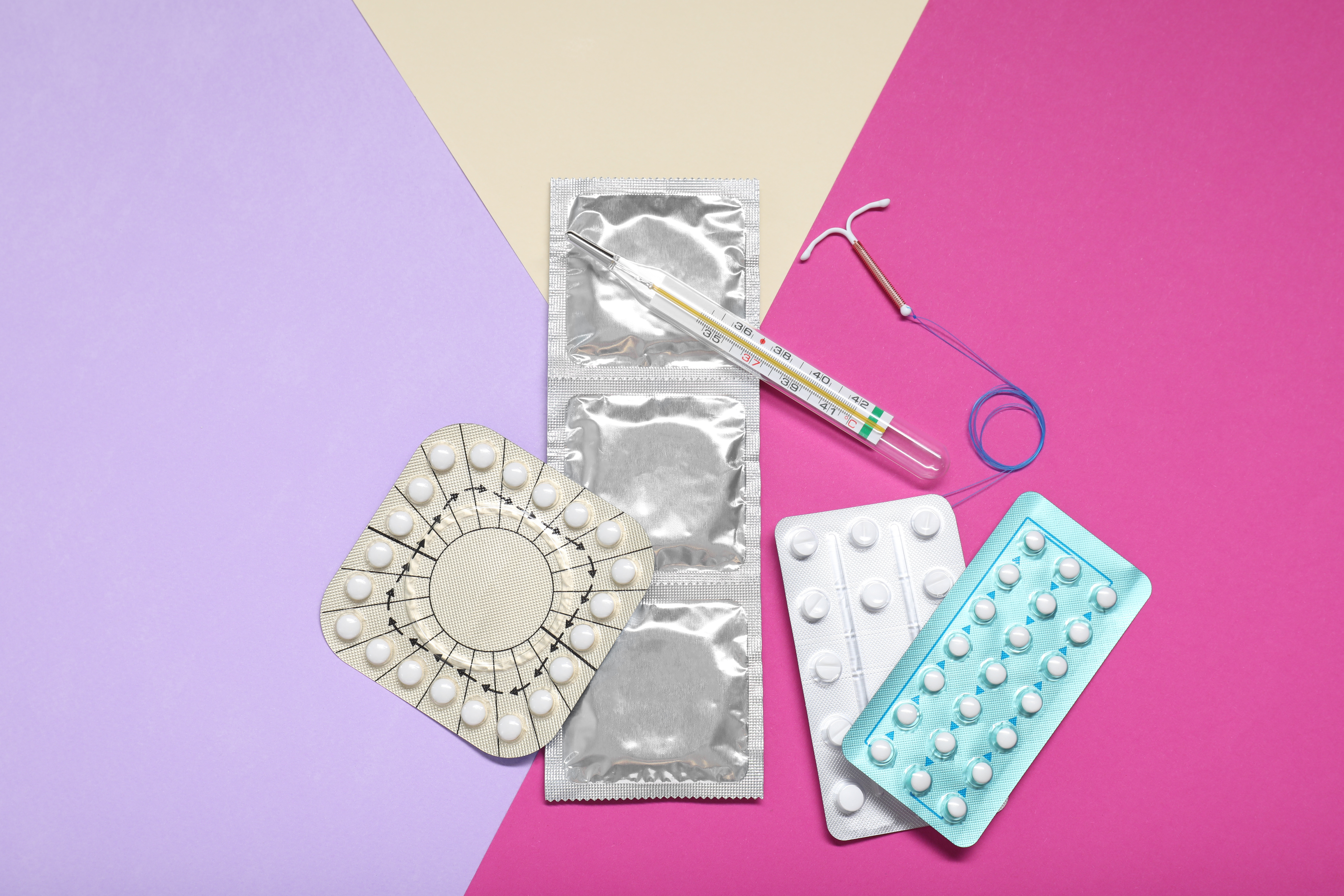 Contraceptive pills, condoms, intrauterine device and thermometer on color background, flat lay. Choice of birth control method Contraceptive pills, condoms, intrauterine device and thermometer on color background, flat lay. Choice of birth control method