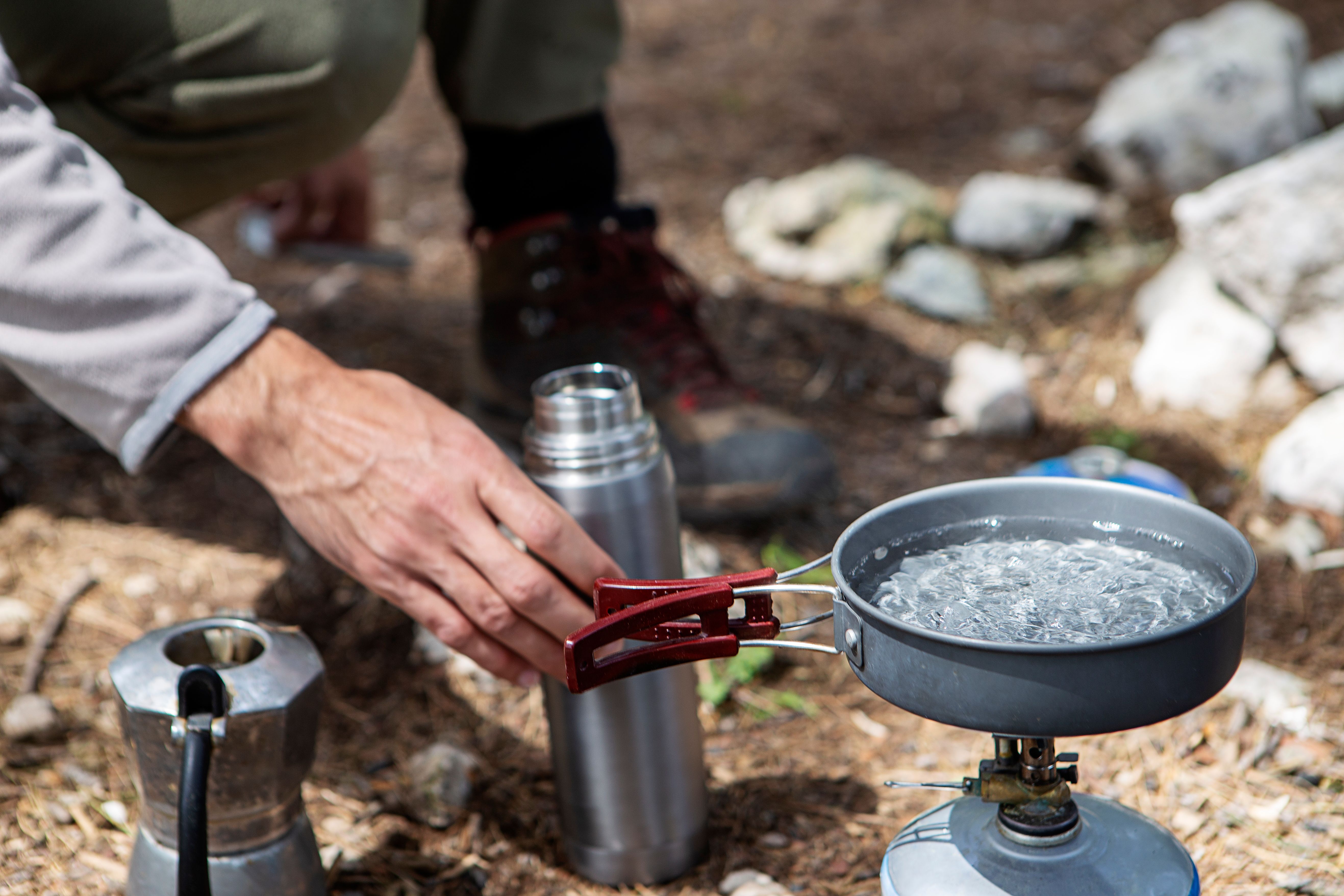 Young camper in the nature boiling water for morning coffee Young camper in the nature boiling water for morning coffee