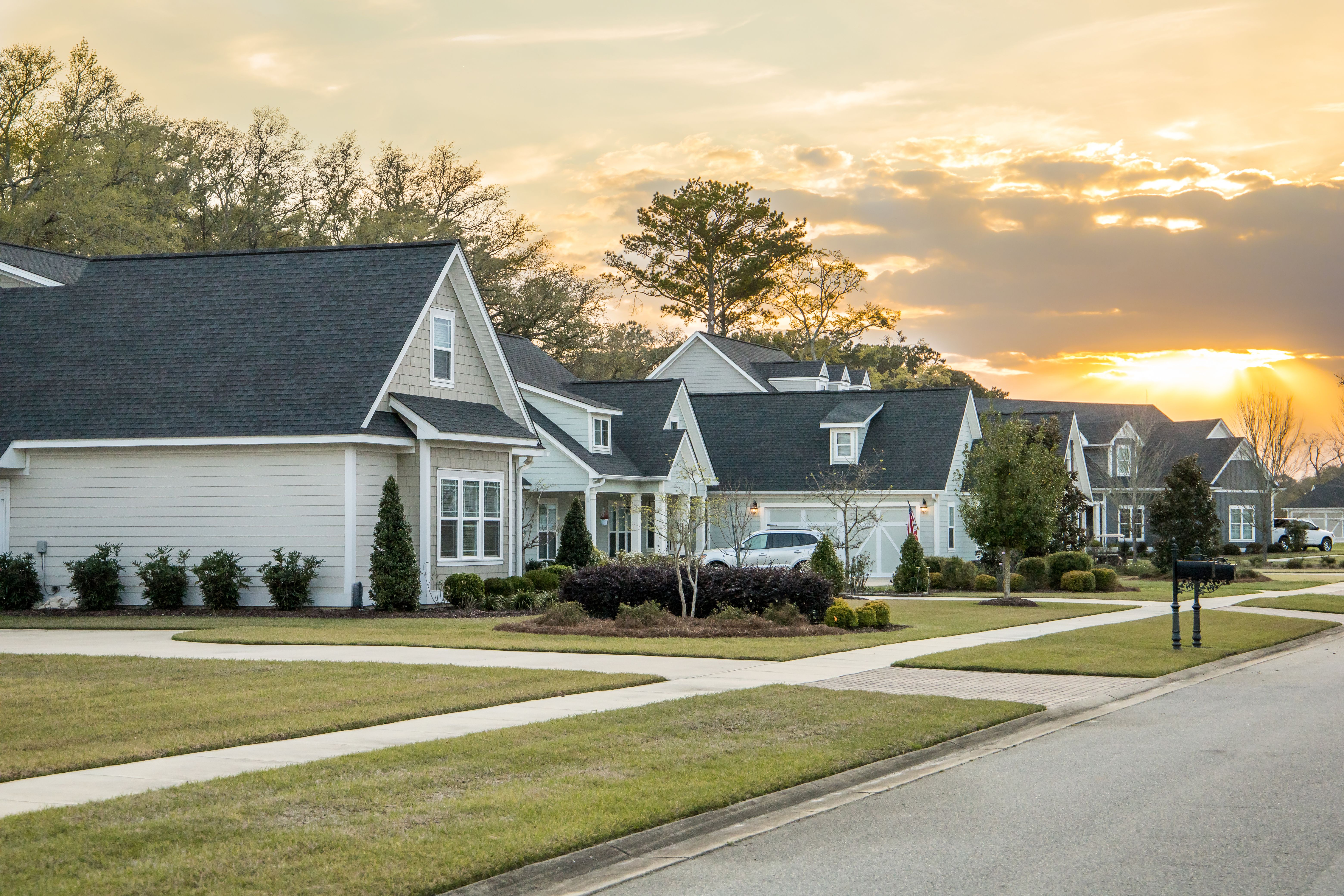 A Street view of a new construction neighborhood with larger landscaped homes and houses with yards and sidewalks taken near sunset A Street view of a new construction neighborhood with larger landscaped homes and houses with yards and sidewalks taken near sunset