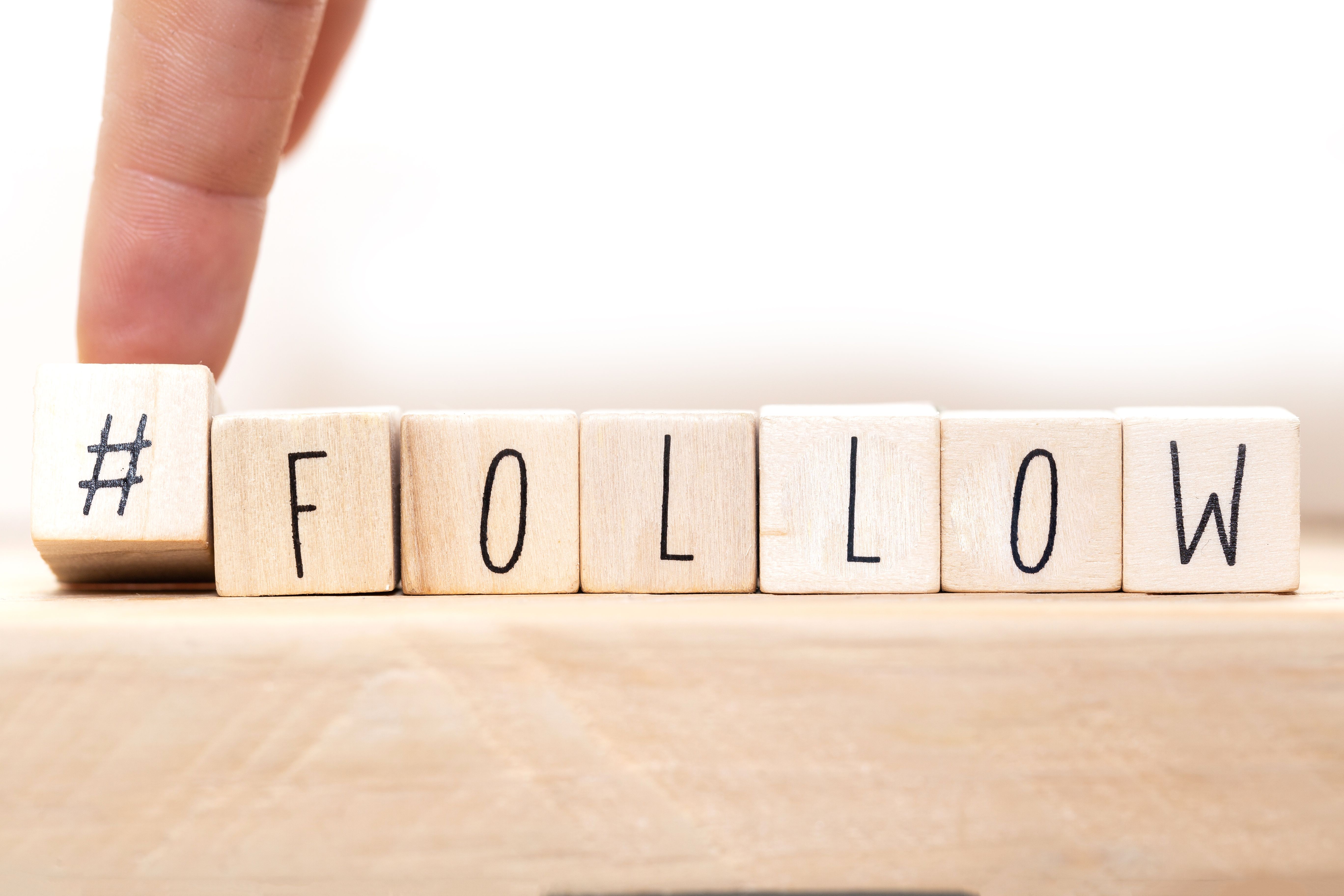 Follow sign made of cubes on a wooden table with Hashtag near white background, socialmedia concept Follow sign made of cubes on a wooden table with Hashtag near white background, socialmedia concept
