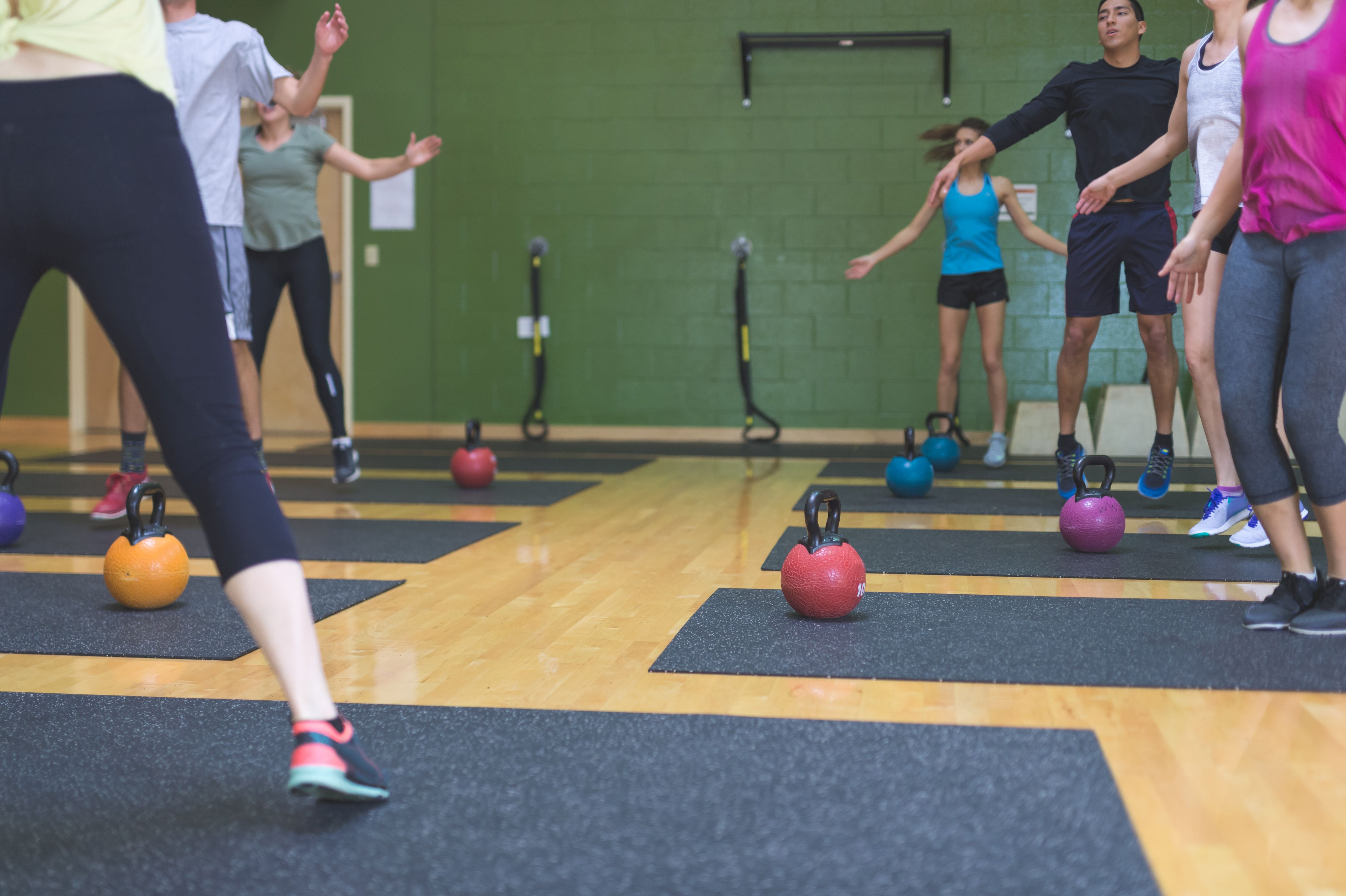 Co-ed group of college-age students exercise together at a modern fitness facility