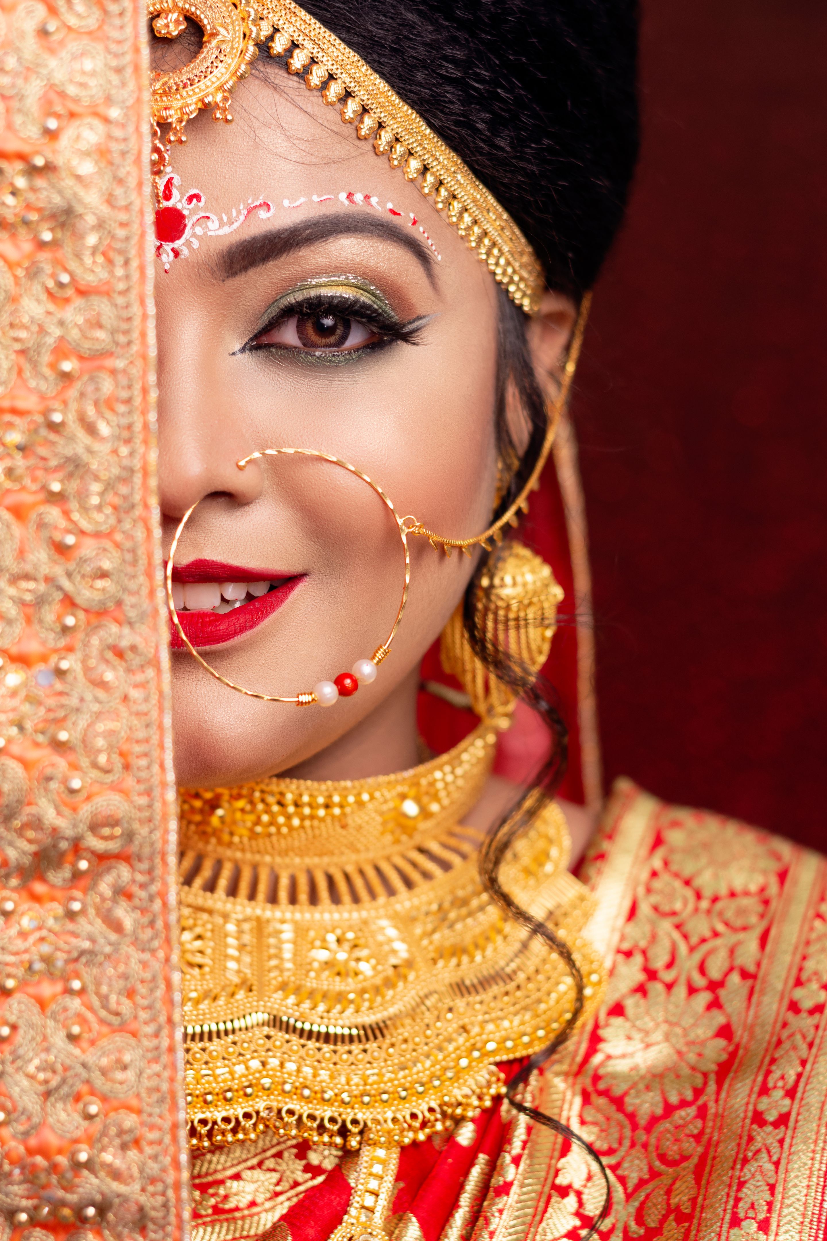 A pretty young female model wearing traditional indian / Bangladeshi bridal outfit with heavy gold jewelry and makeup