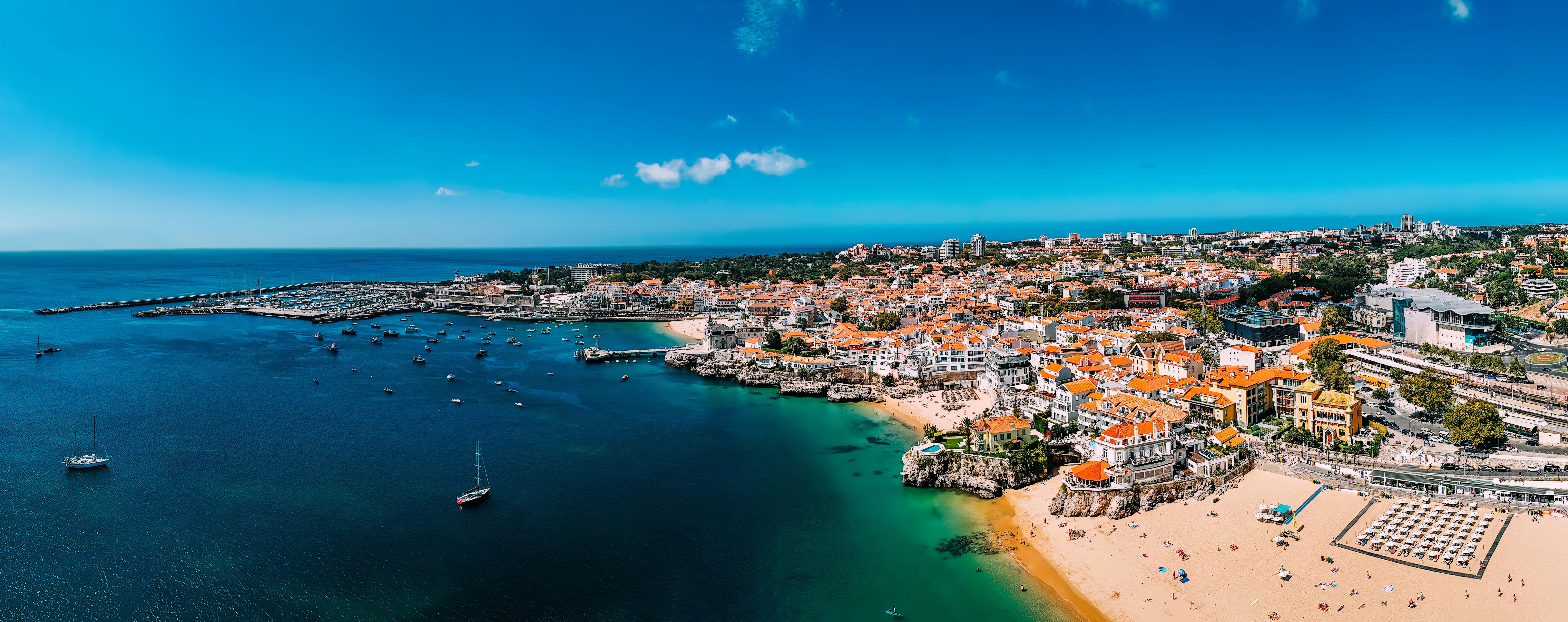 A panoramic view of Cascais, Portugal showcasing vibrant coastal life, sandy beaches, and clear waters on a sunny day