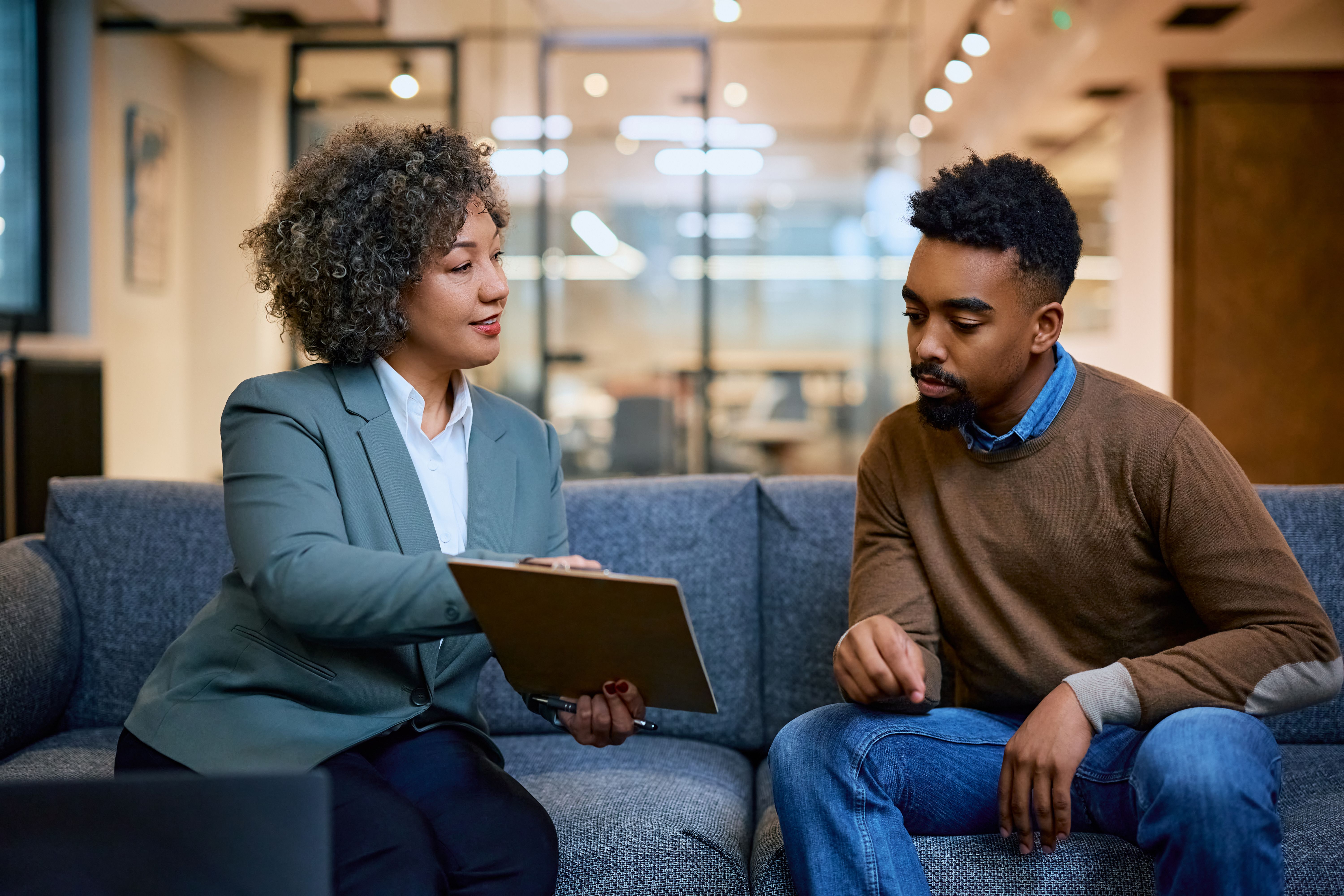 Financial advisor consulting African American man while going through paperwork on a meeting in the office.