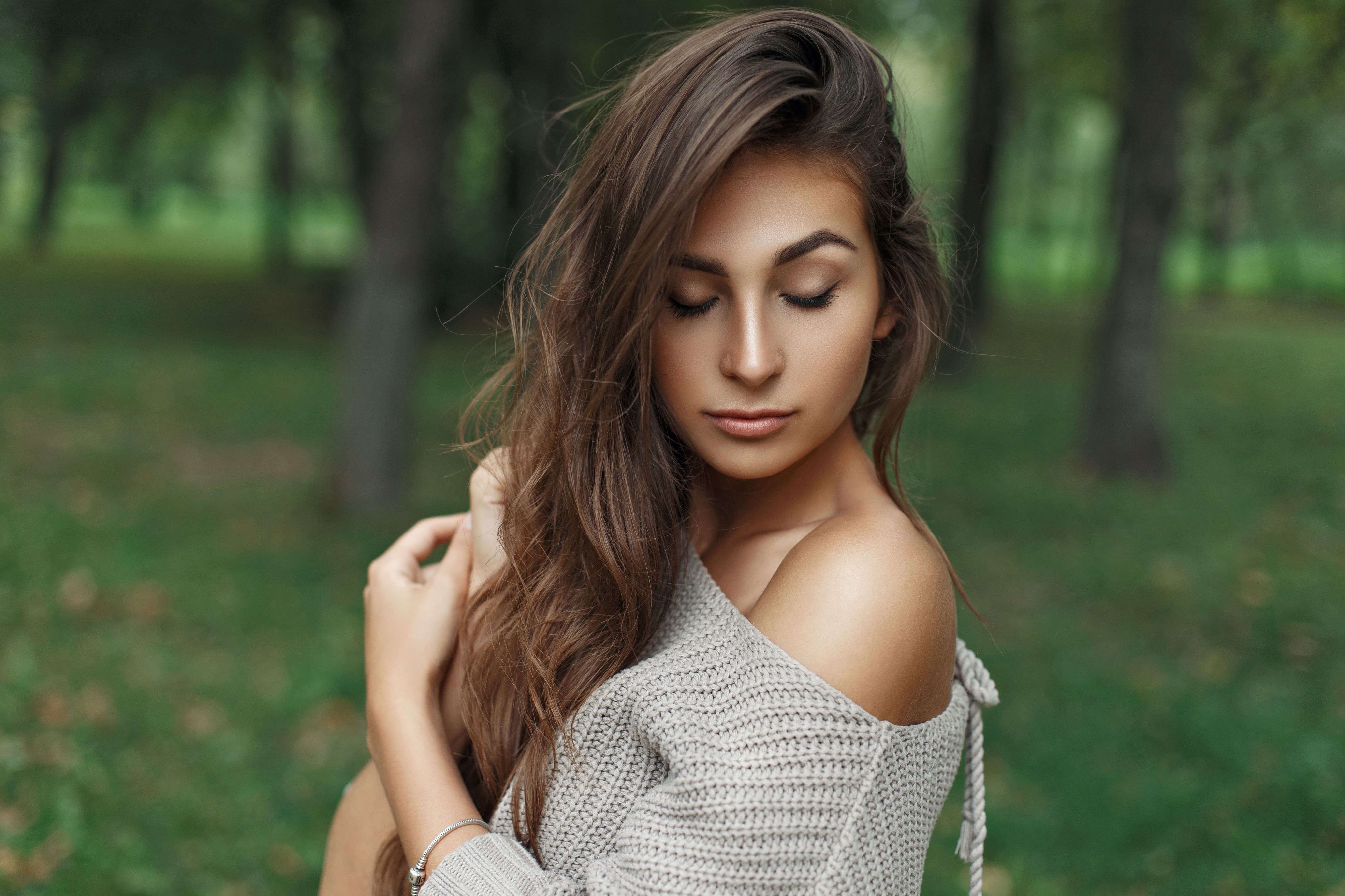 Beautiful young model girl with hairstyle in a knitted sweater in the park