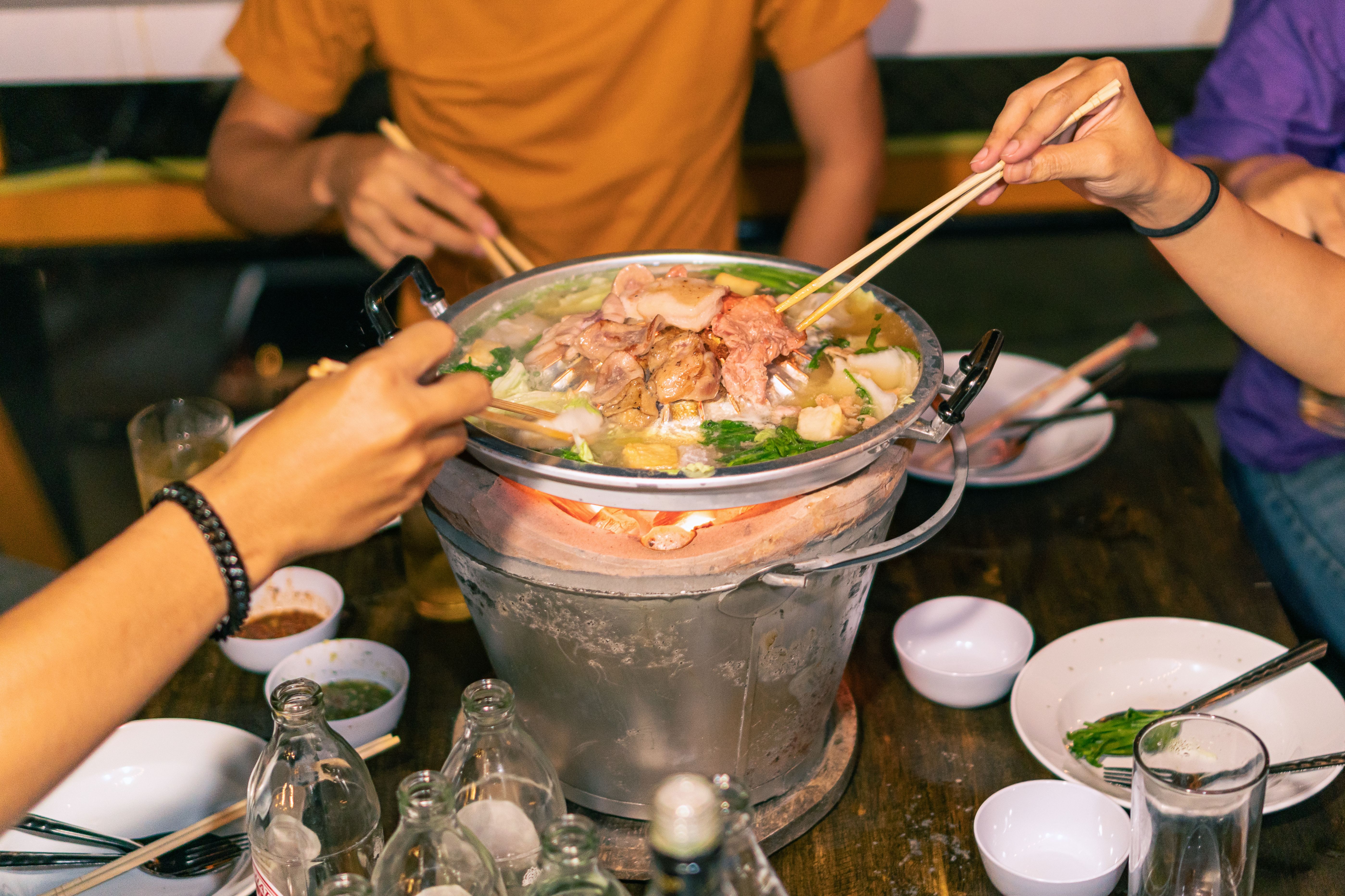 Hand holding chopsticks eating Thai barbecue, popular street food
