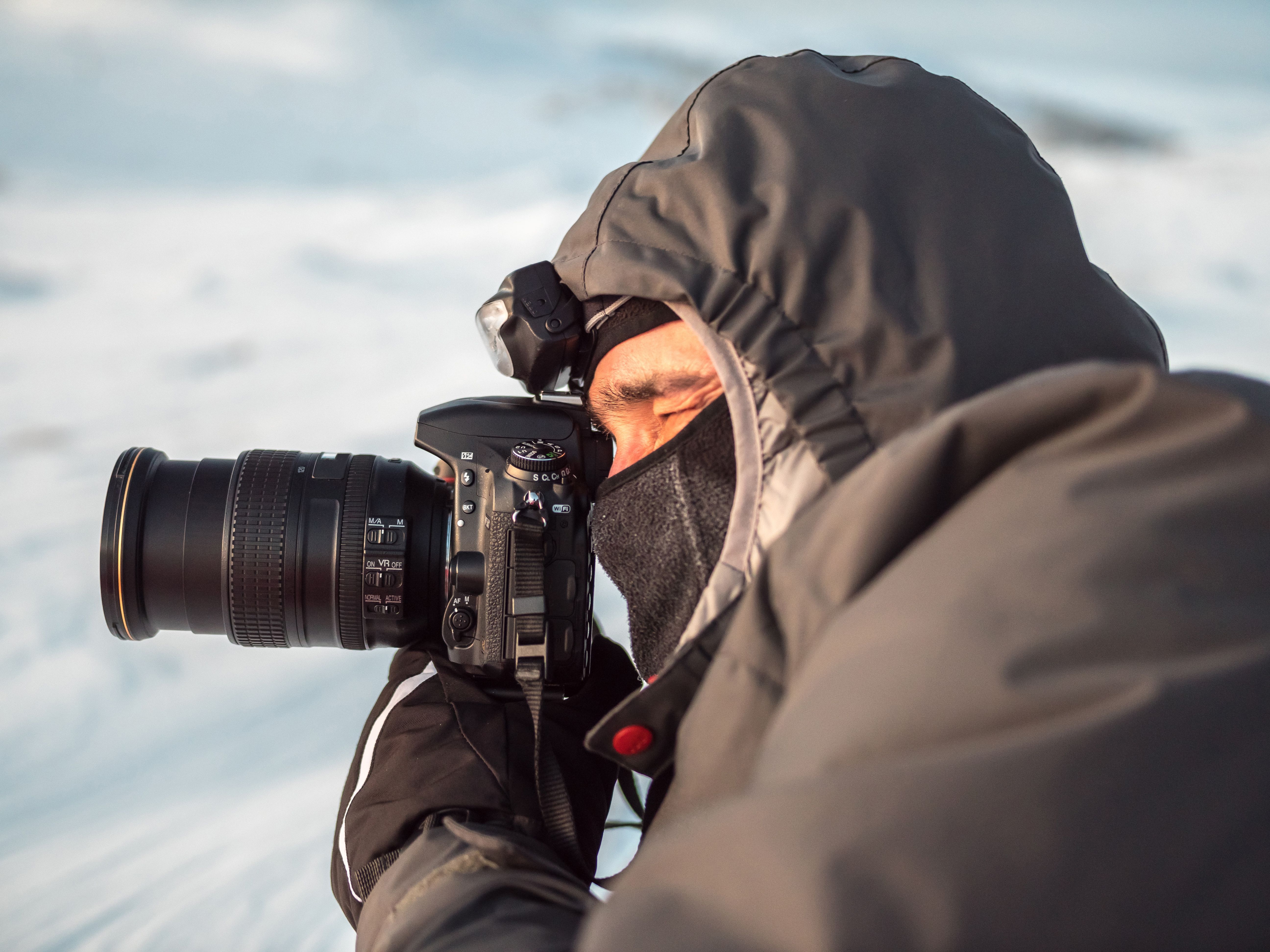 Close-up do fotógrafo deitada na neve e fotografar