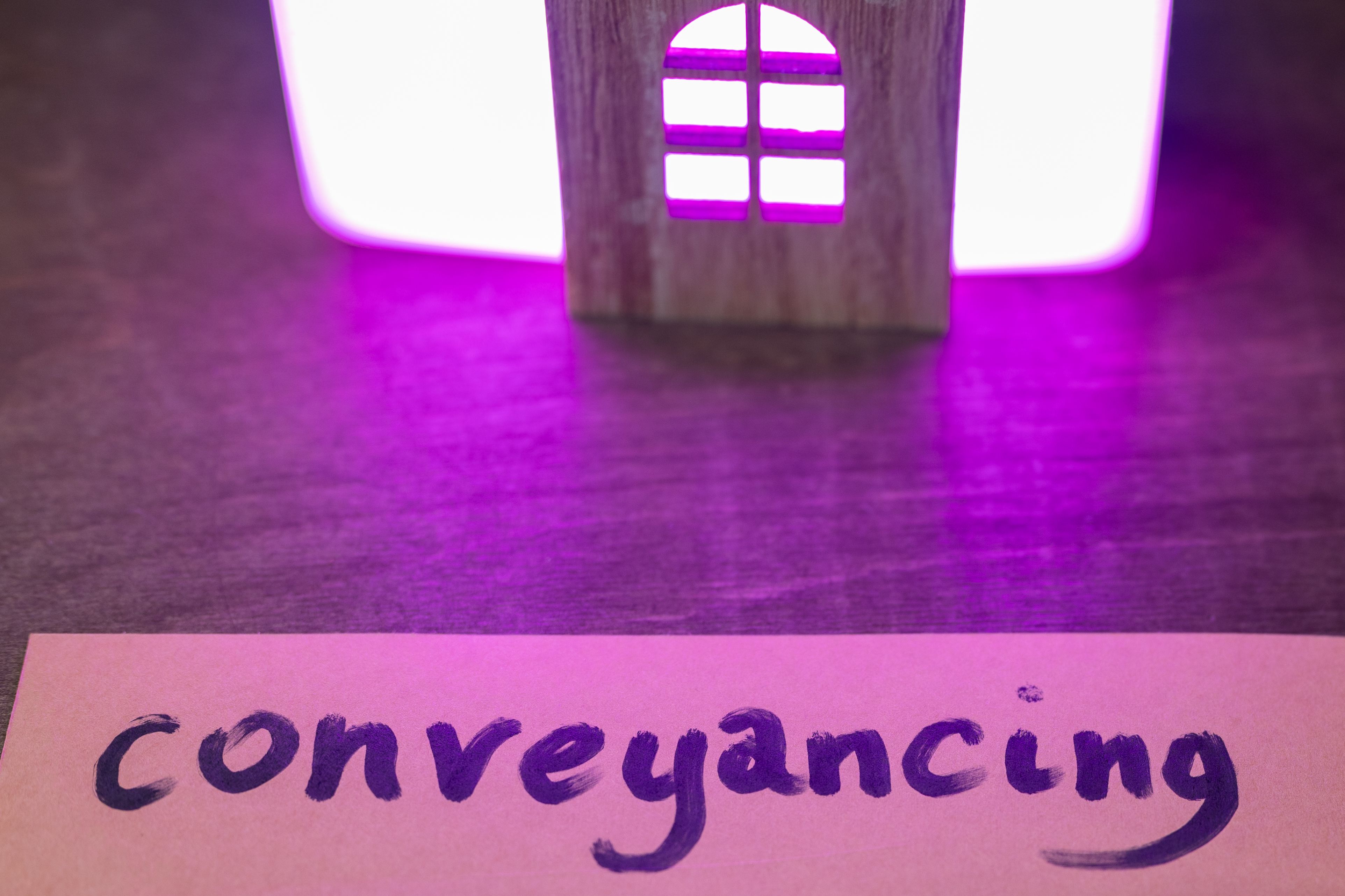 a cut out wooden house representation with a key and a card saying 'conveyancing'
