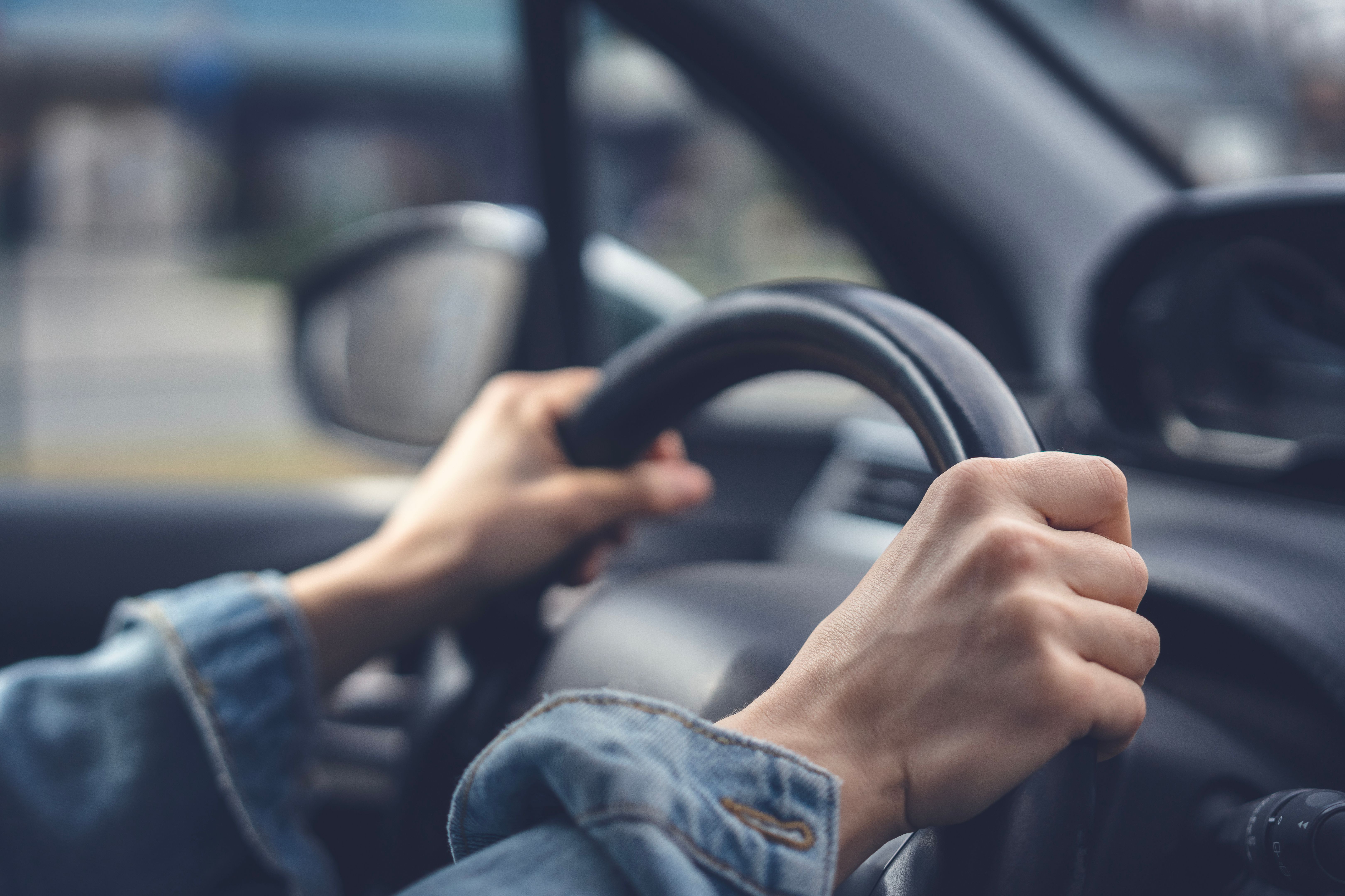 Tense hands of a female driver on the steering wheel in a car. Stress while driving a car