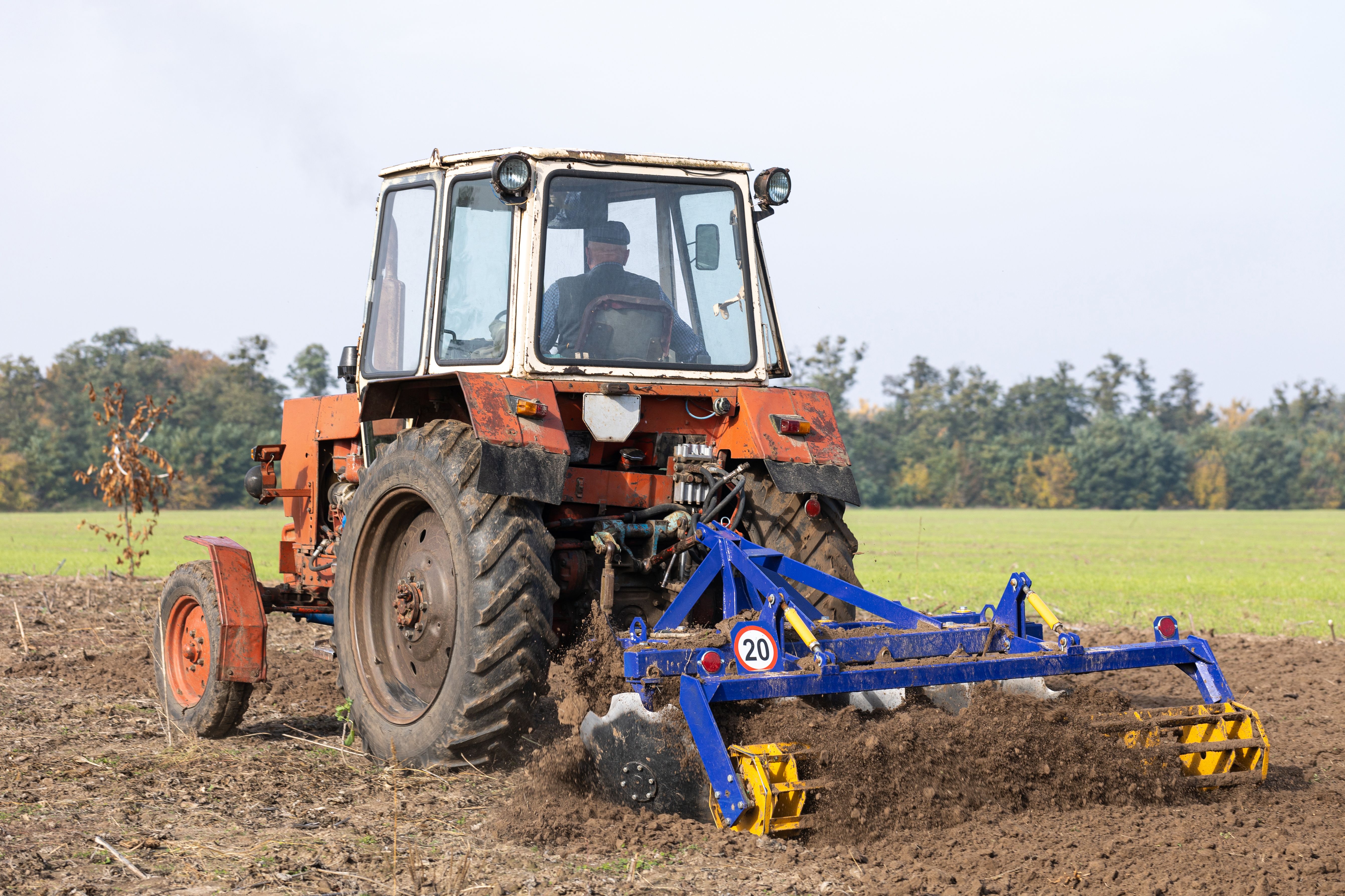 The tractor plows the soil with discs in a field. The tractor plows the soil with discs in a field.