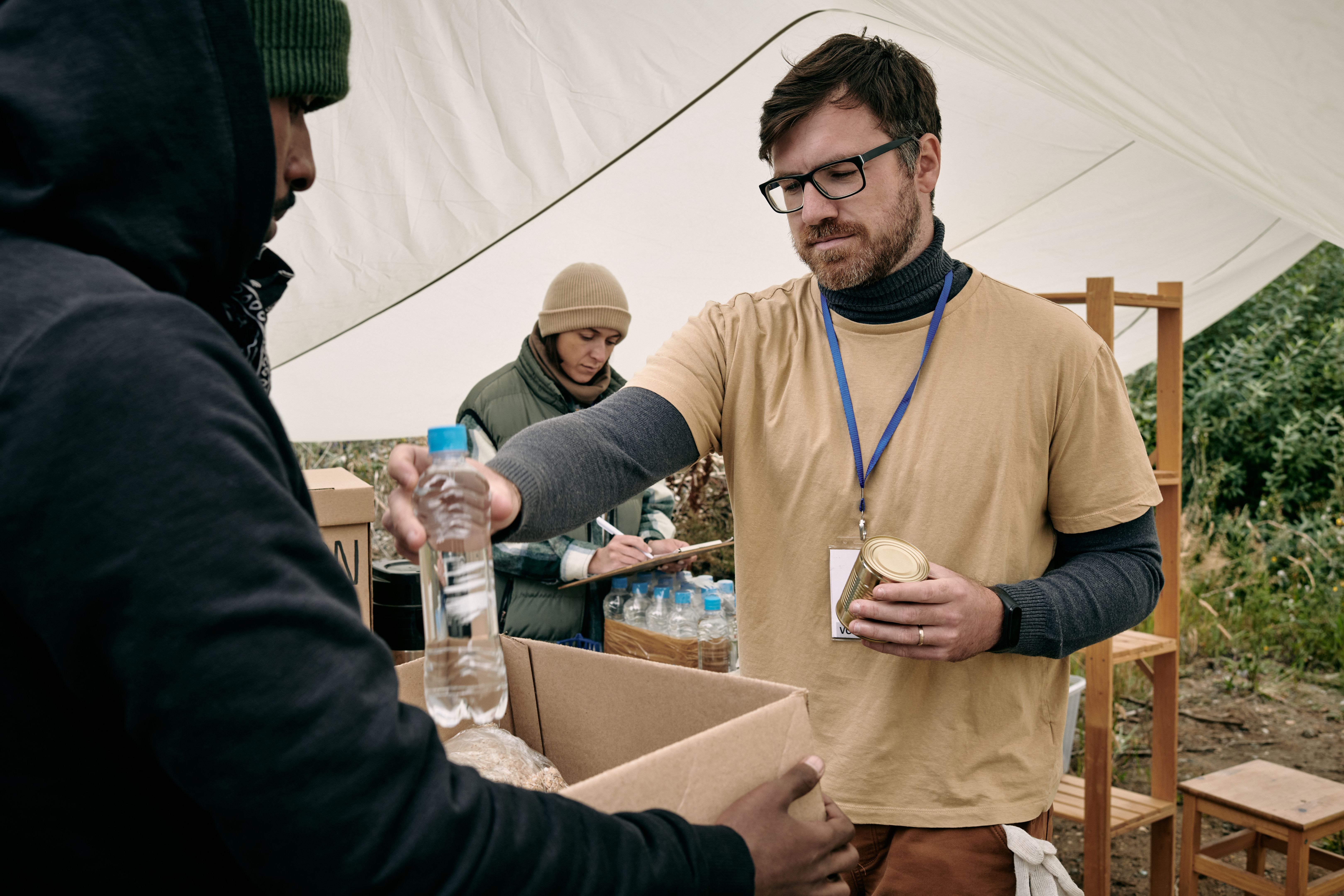 Volunteer Giving Water To Homeless Man