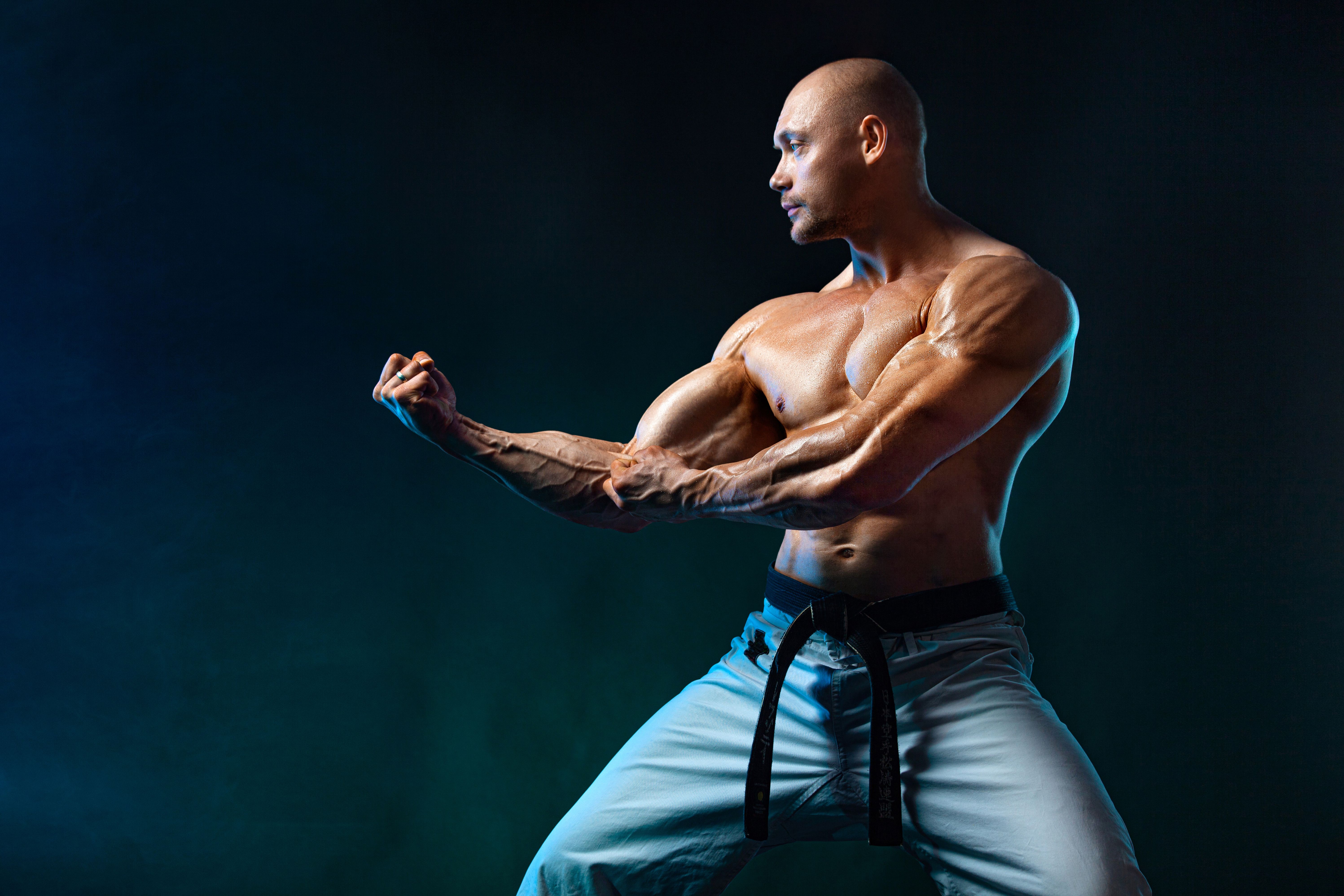 Karate or taekwondo fighter on black background with smoke. Fit man sportsmen bodybuilder physique and athlete. Men's sport motivation.