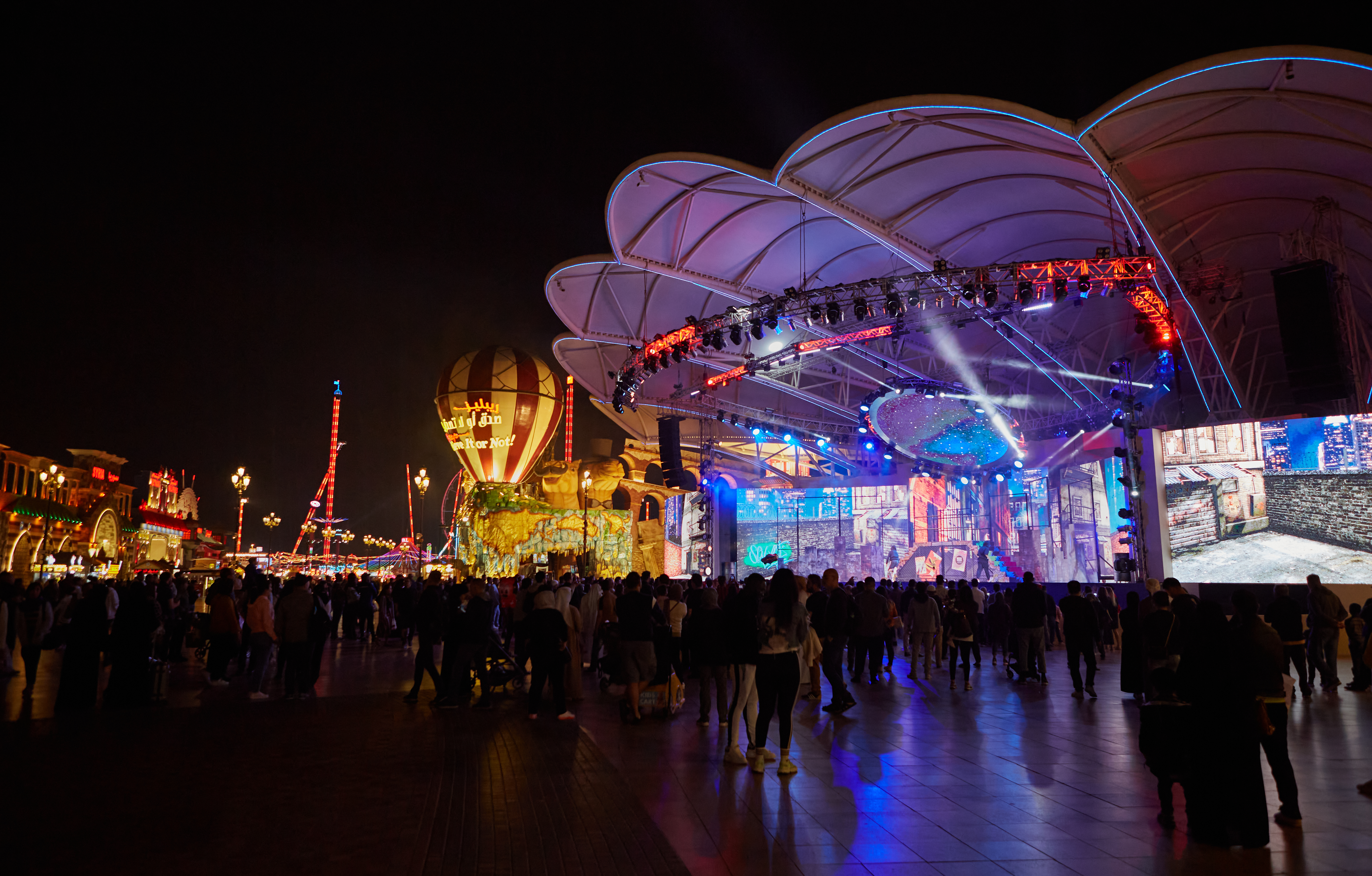 Large group of tourists enjoying the show at the Global Village at night.