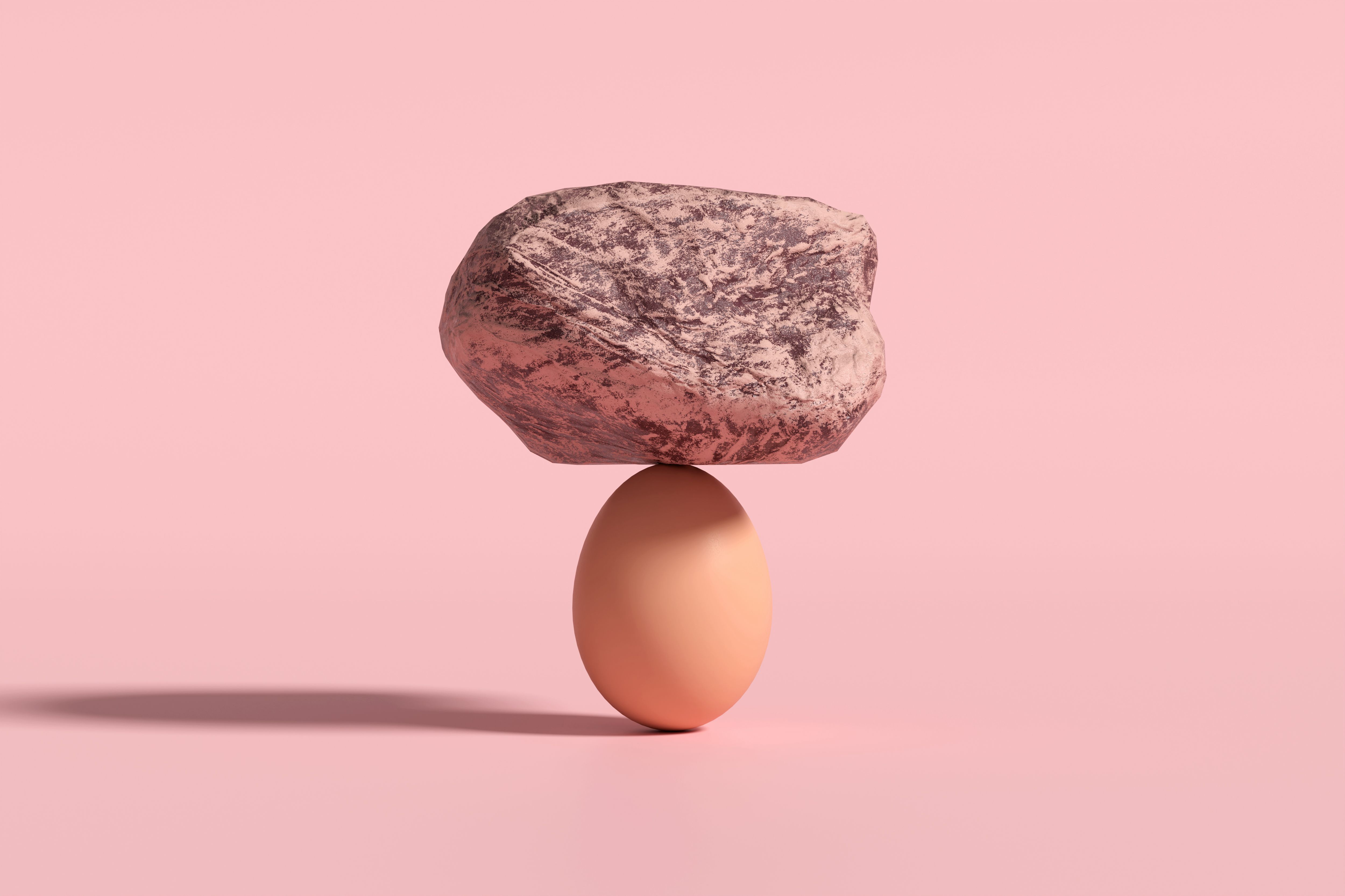 Big rock balancing on a fragile egg on a pink background