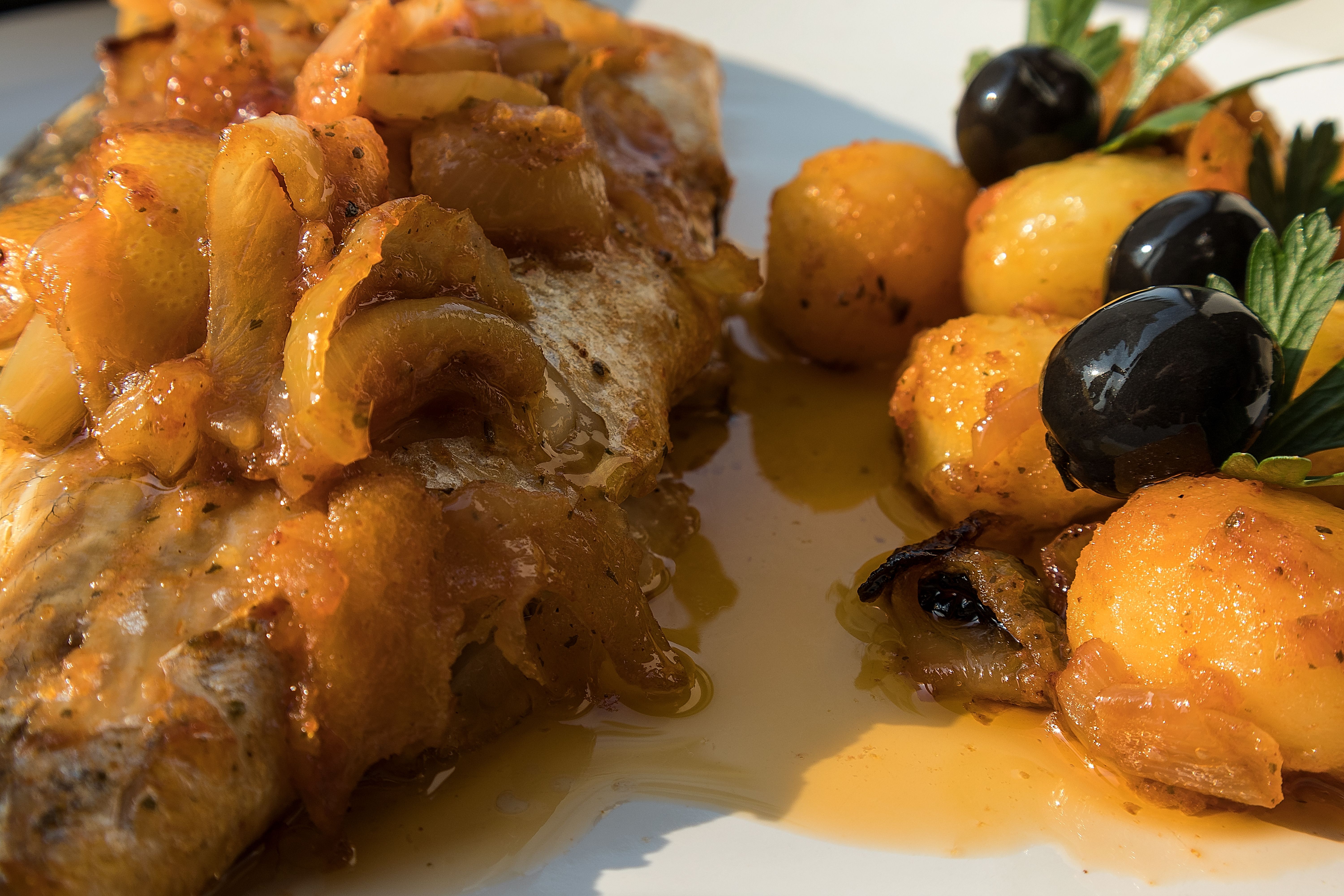 Pesce cotto in forno, dorato con patate bollite e olive in piatto bianco. Piatto tipico portoghese. Pesce cotto in forno, dorato con patate bollite e olive in piatto bianco. Piatto tipico portoghese.