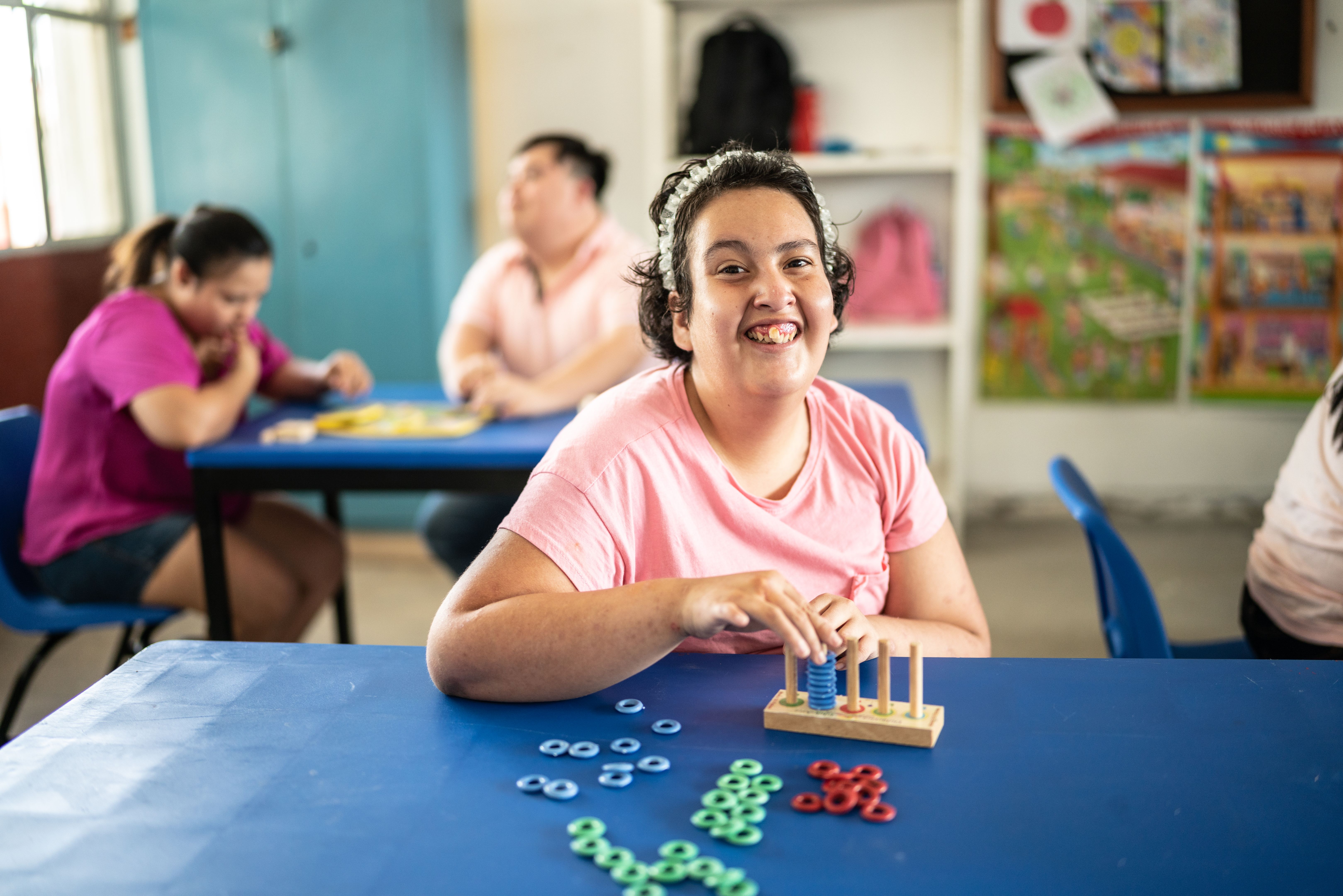 Portrait of a psychomotor Intellectual disability teenage girl playing didactic game in the classroom at school