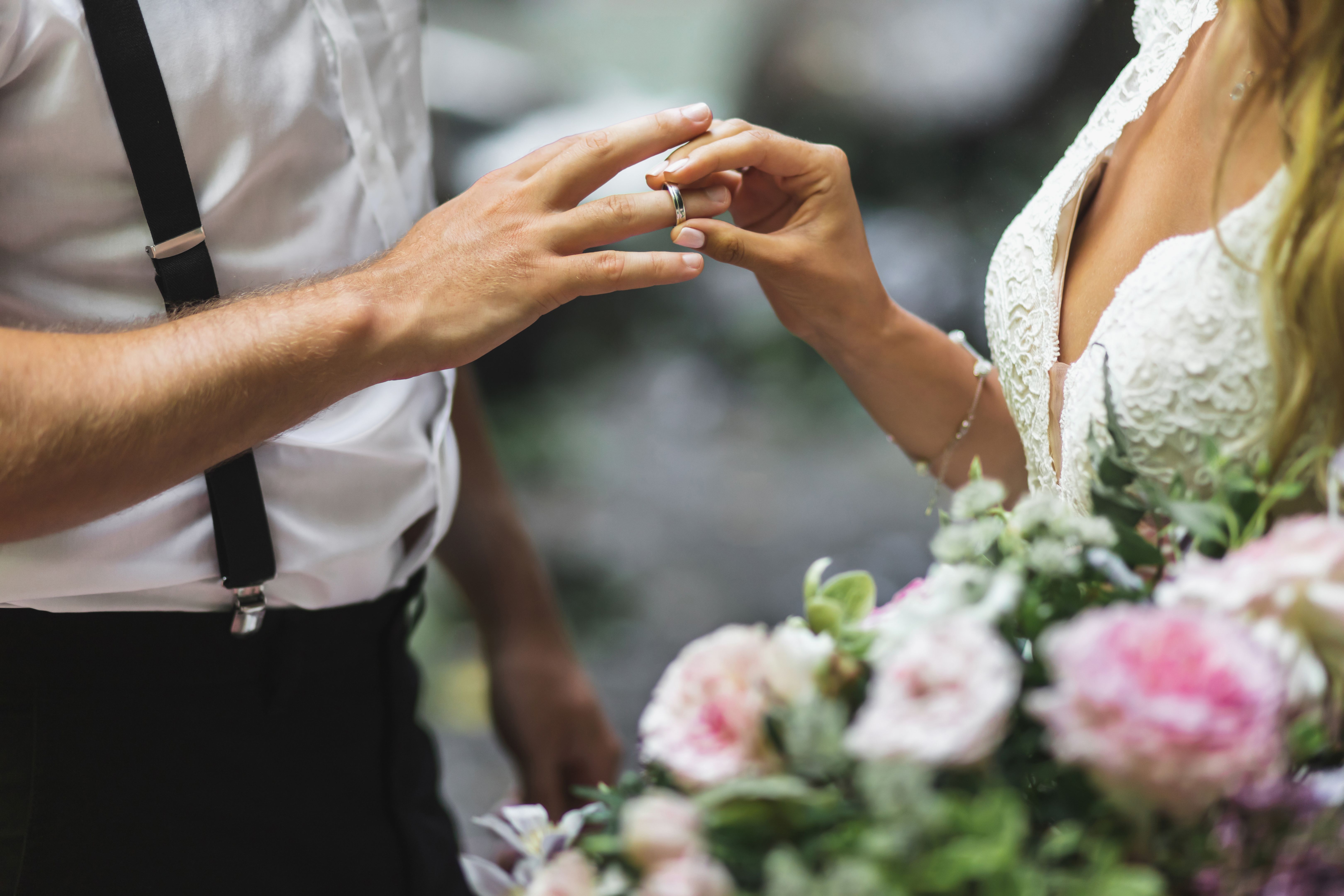 Bride putting wedding ring on groom's hand close up. Symbol of love and commitment. Wedding ceremony vows.