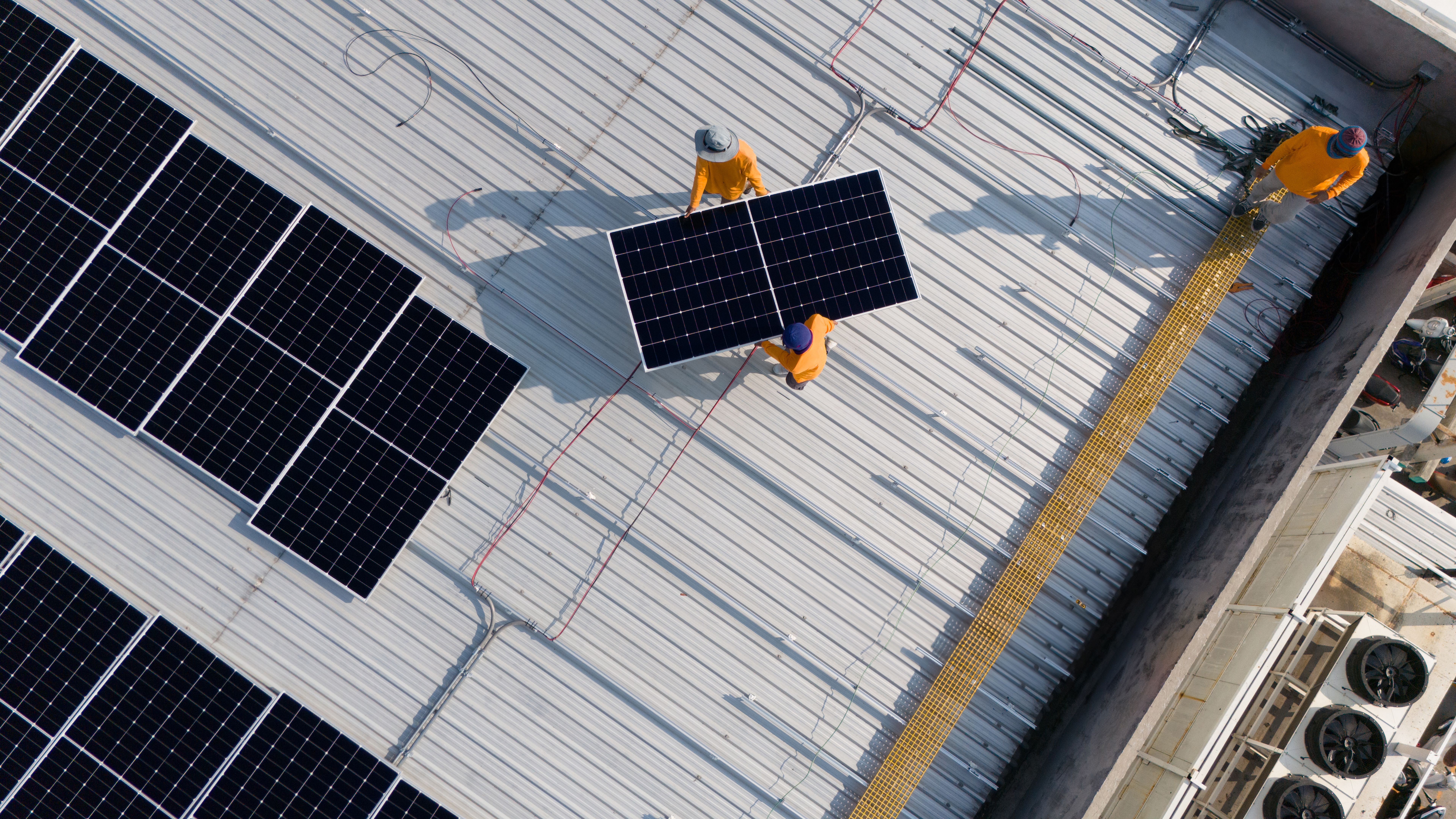 Aerial top view of a technician drone installing solar panels on the roof.