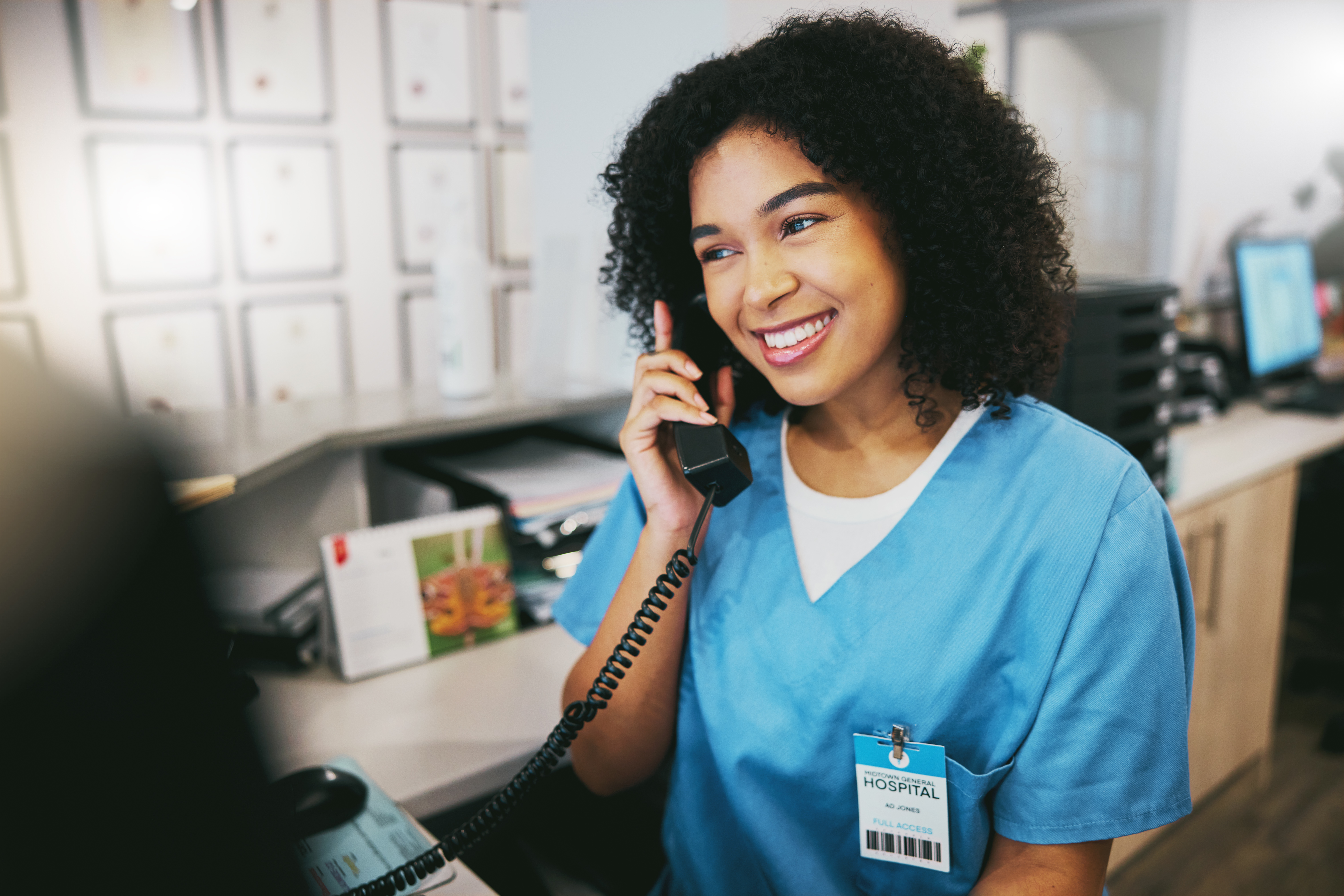 Nurse, phone call and black woman with happiness at doctor office with a smile. Clinic, healthcare worker and networking of a young person happy about work conversation and health insurance talk