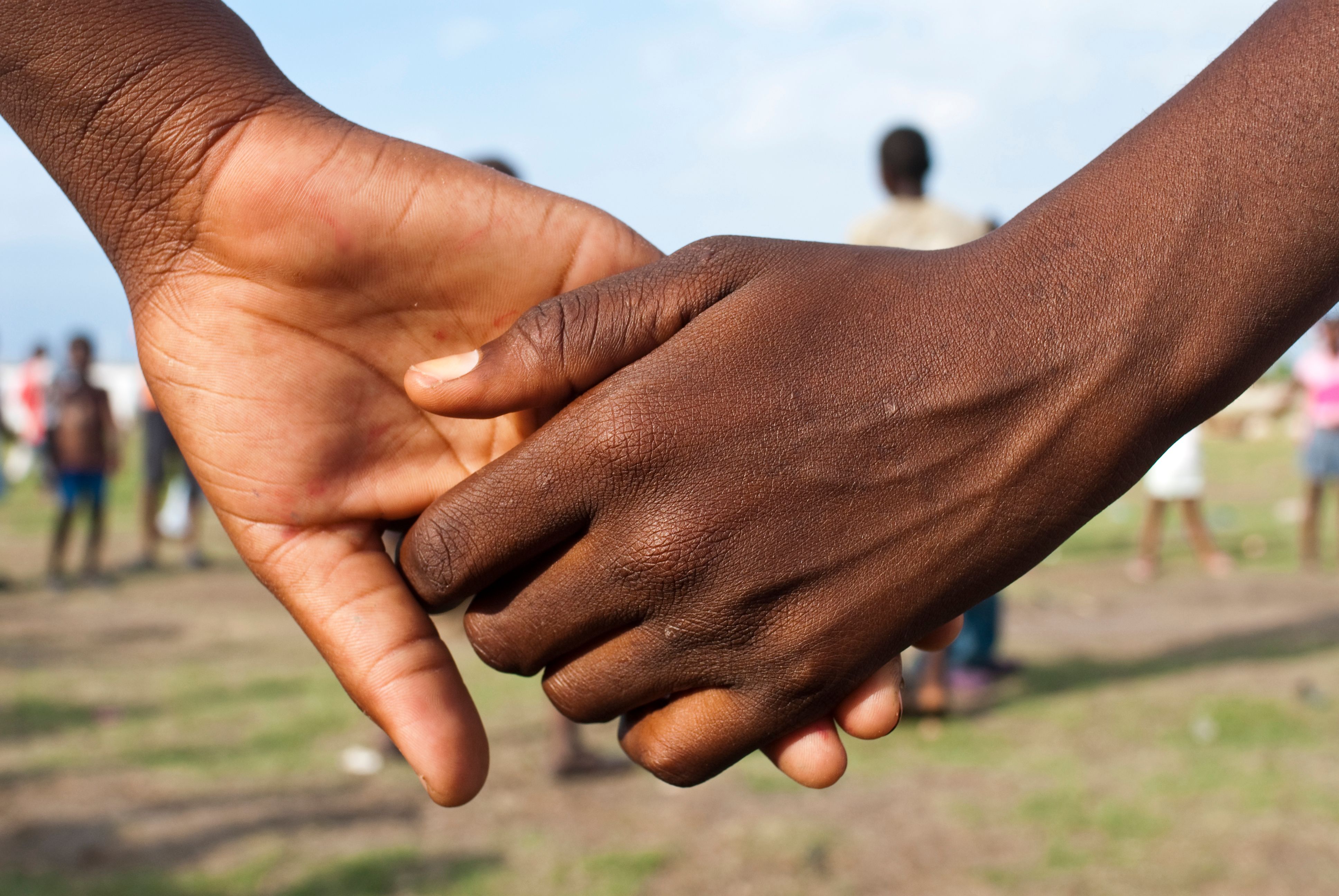Close-up of two people holding hands in a field Close-up of two people holding hands in a field