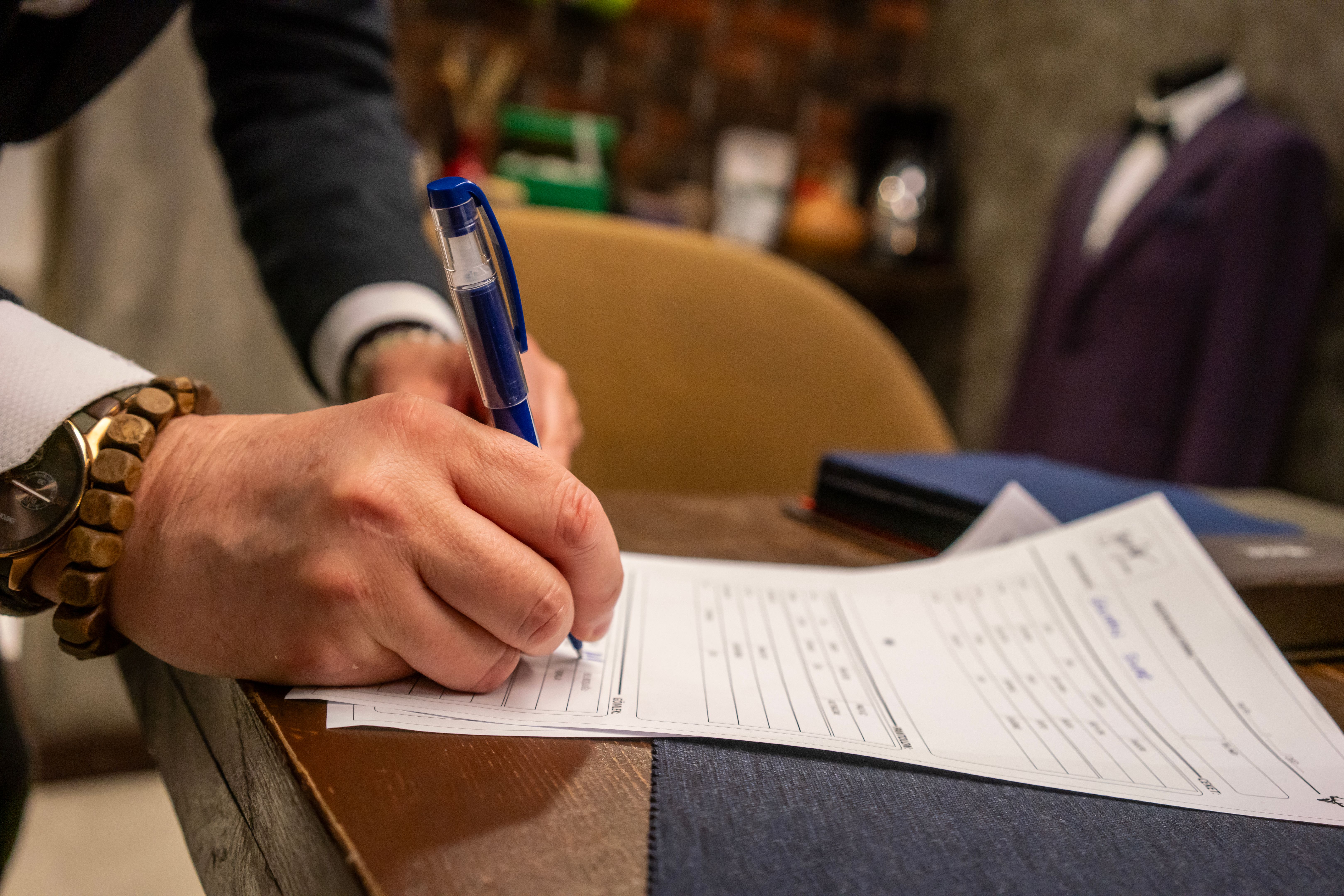 man fashion designer is writing to paper in his studio focus on foreground studio is background horizontal working with hands still