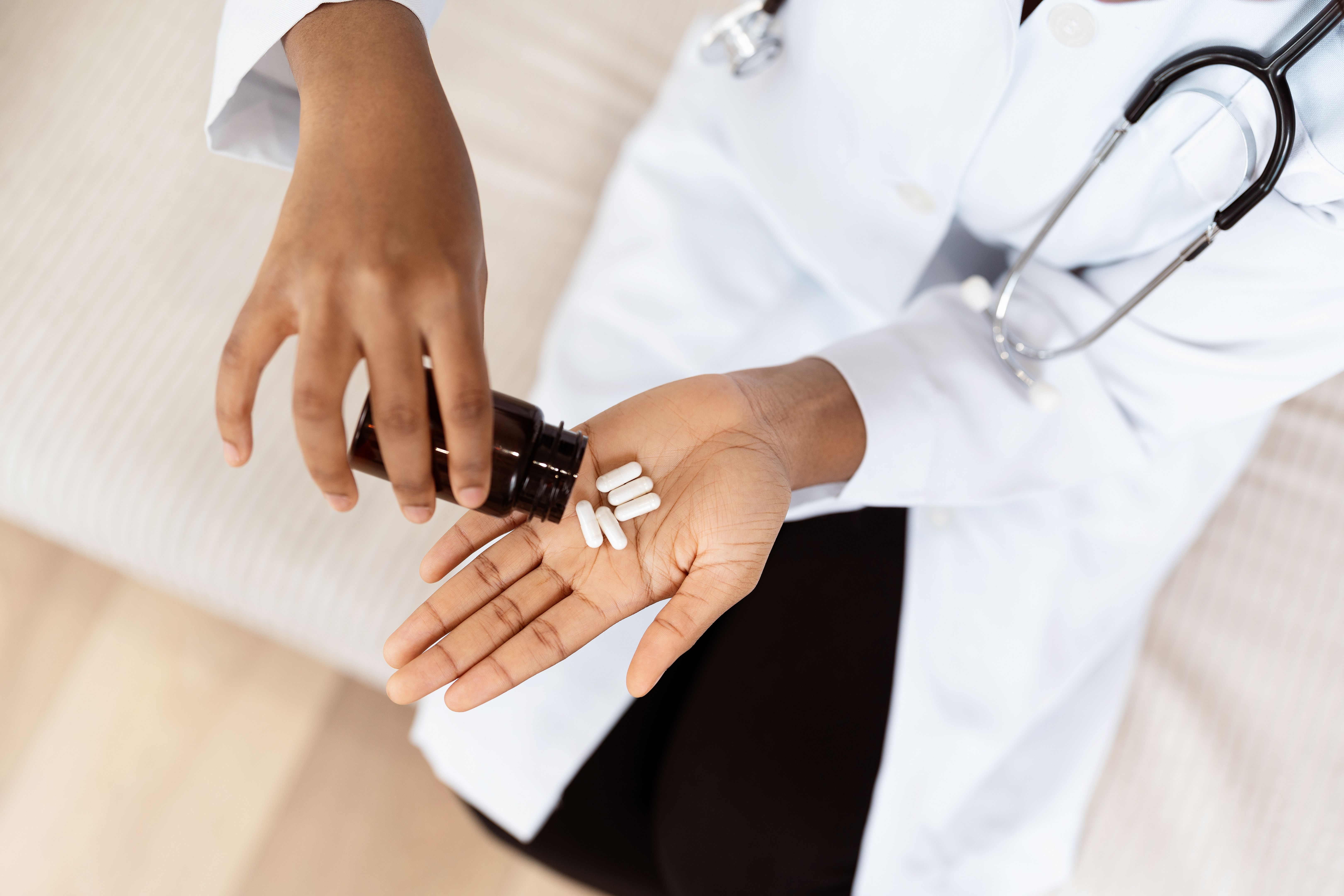 Doctor Pouring White Pills into Hand from Brown Bottle Doctor Pouring White Pills into Hand from Brown Bottle