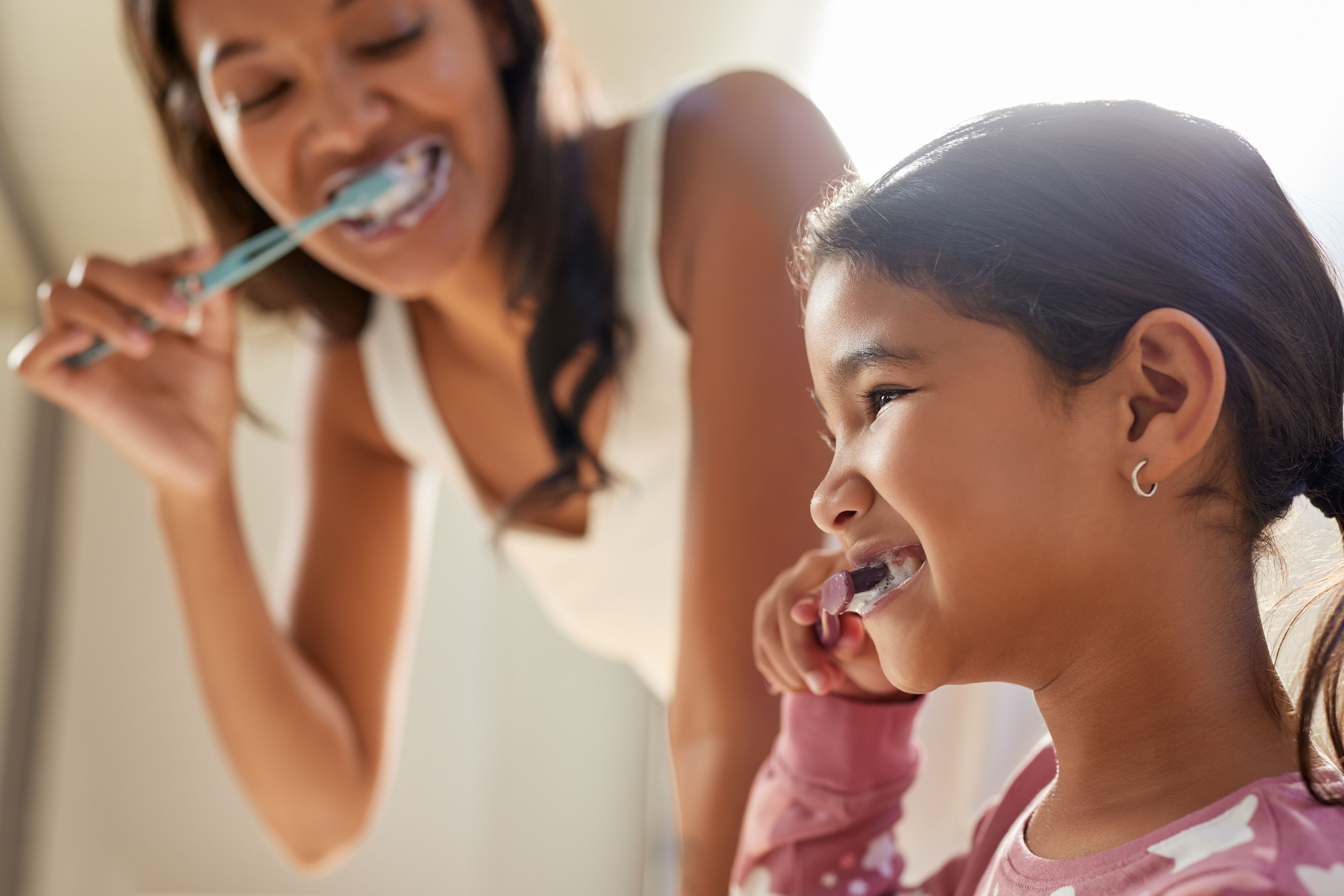 Indian mother and cute little girl brushing teeth together Indian mother and cute little girl brushing teeth together