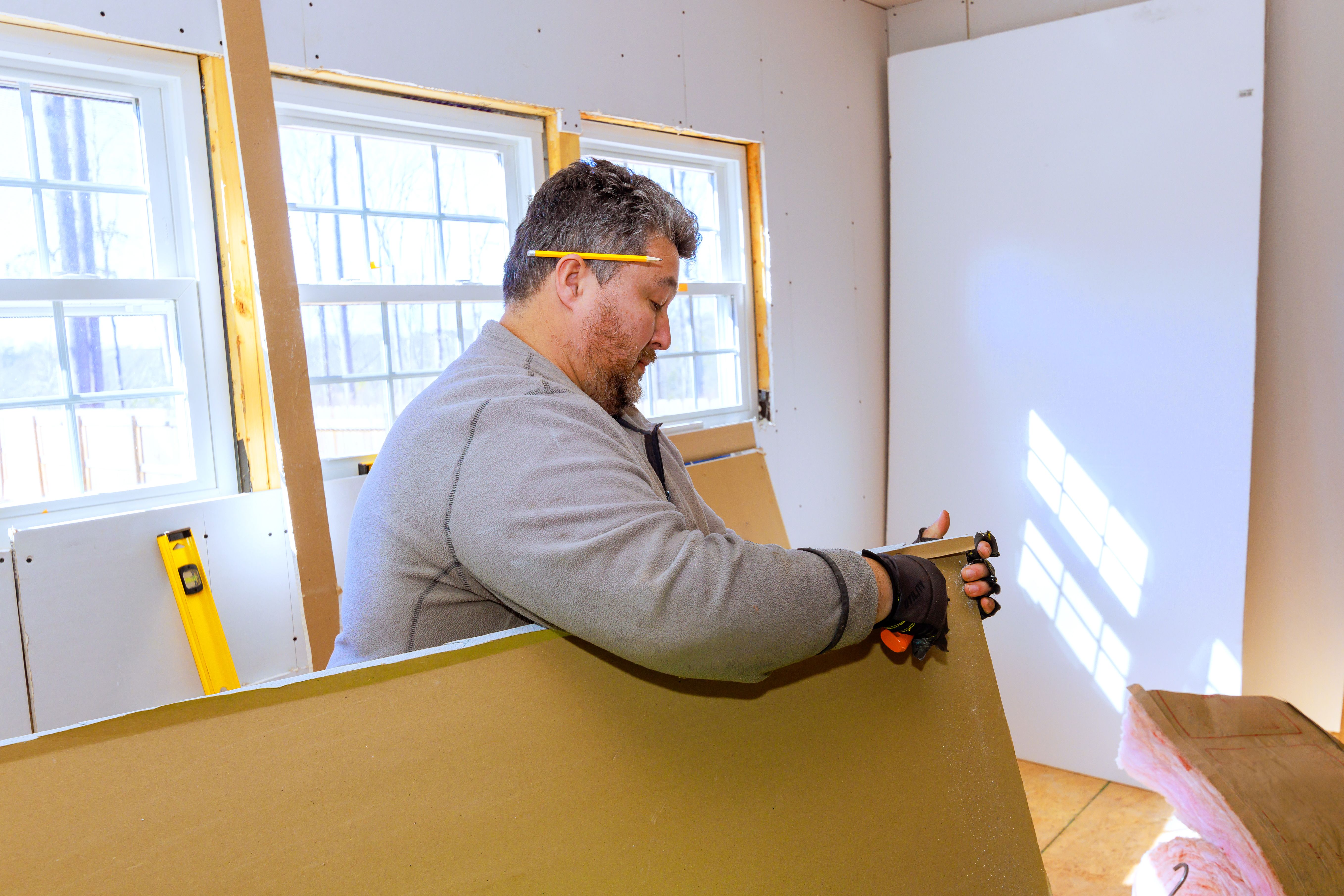 Skilled worker installs drywall in bright interior space during home renovation project