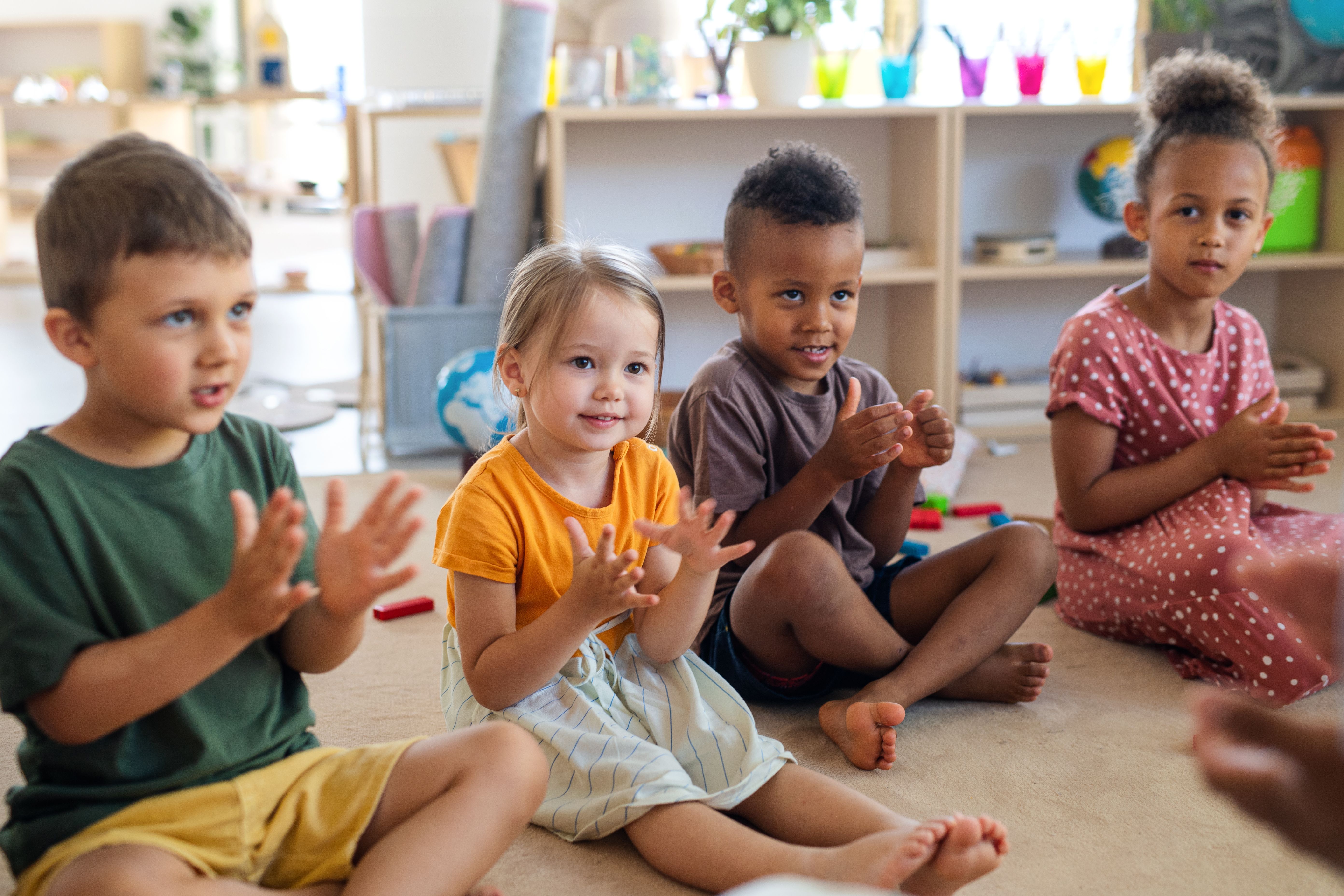 Group of small nursery school children sitting on floor indoors in classroom, clapping. Group of small nursery school children sitting on floor indoors in classroom, clapping.