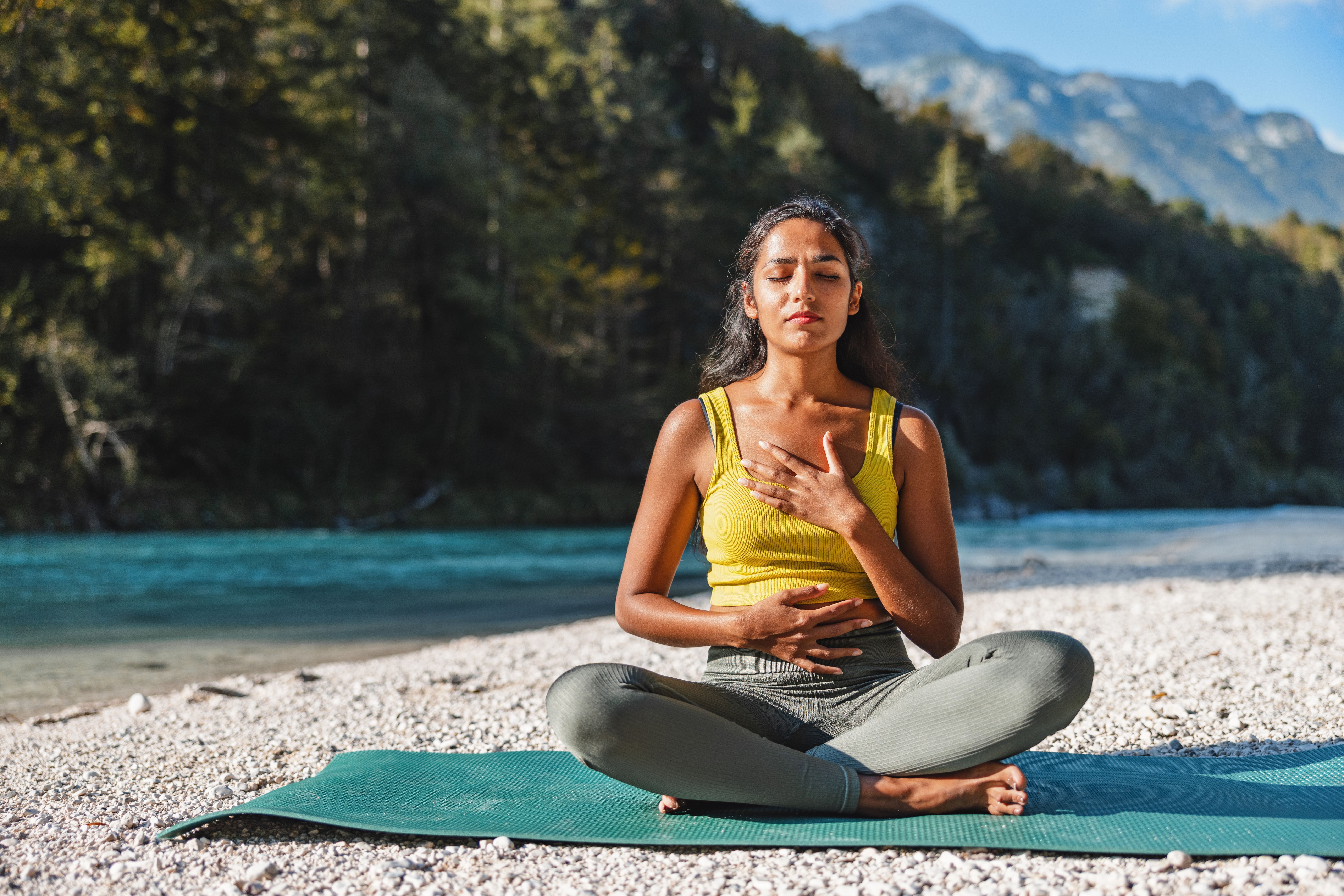 Young Woman Practicing Yoga Outdoors by River Young Woman Practicing Yoga Outdoors by River