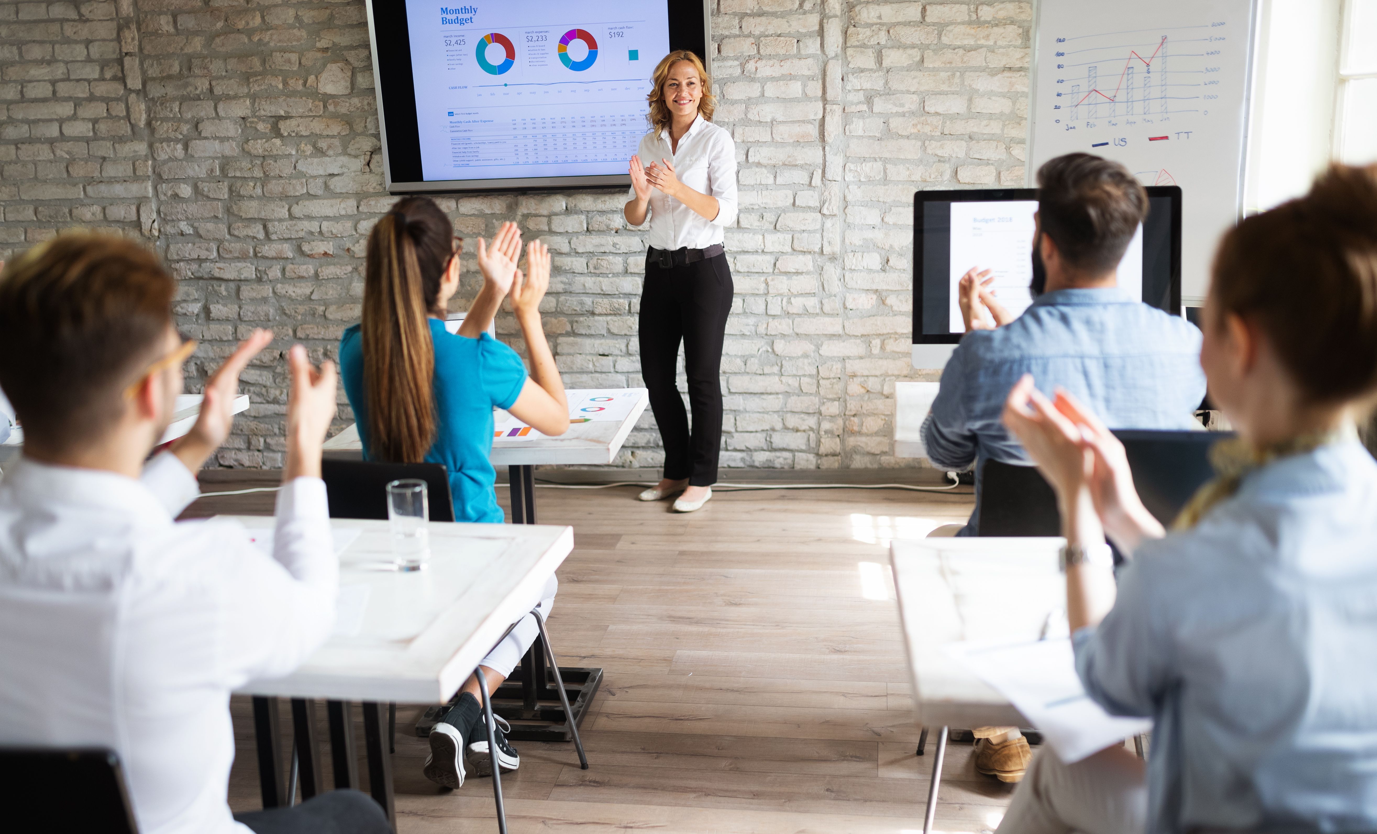 Trenerka podczas prezentacji fundacji Healio Studio omawia wyniki badań i projekty wspierające zdrowie psychiczne. Uczestnicy biorą udział w spotkaniu edukacyjnym.