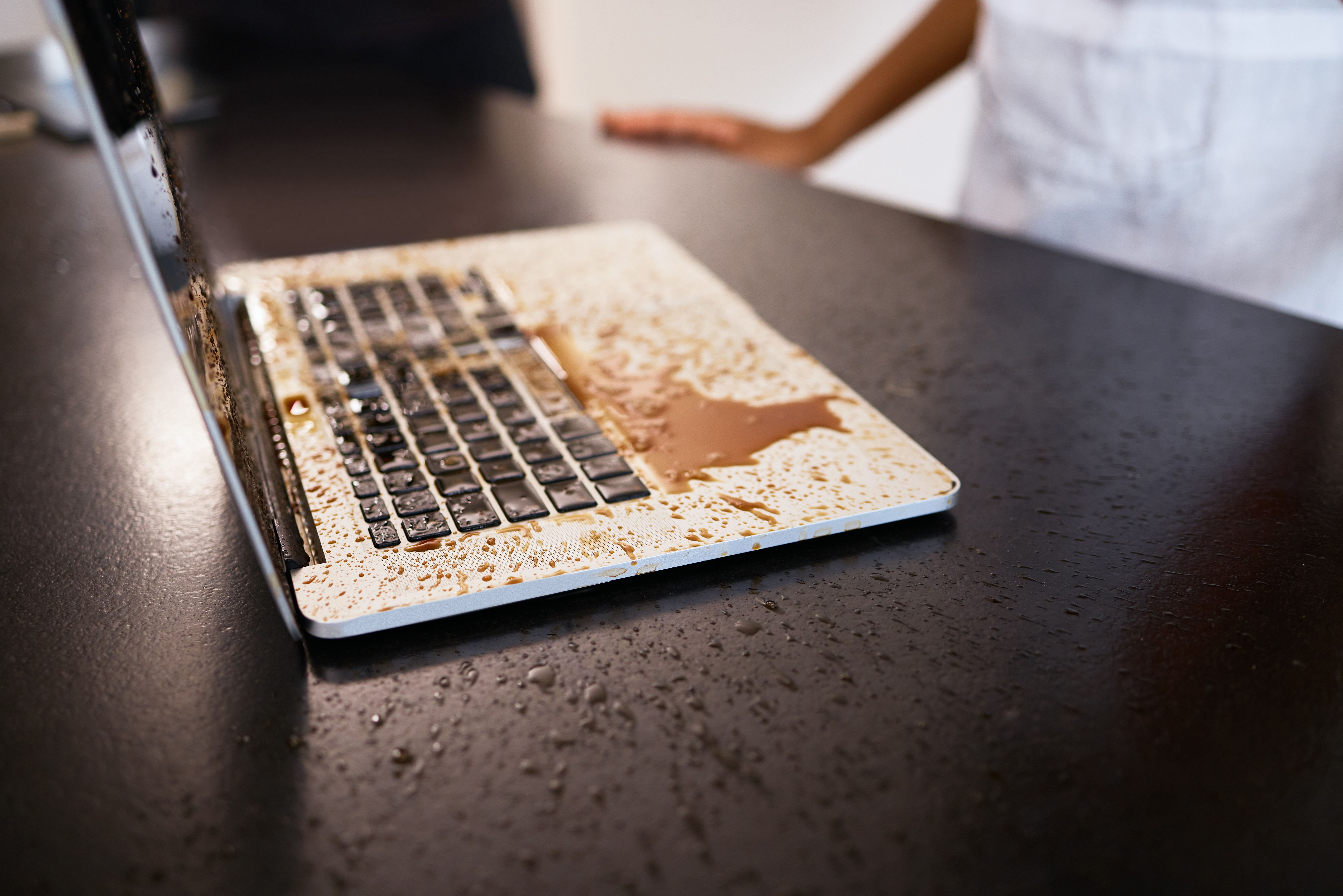 Closeup shot of coffee spilt over a laptop on a table Closeup shot of coffee spilt over a laptop on a table