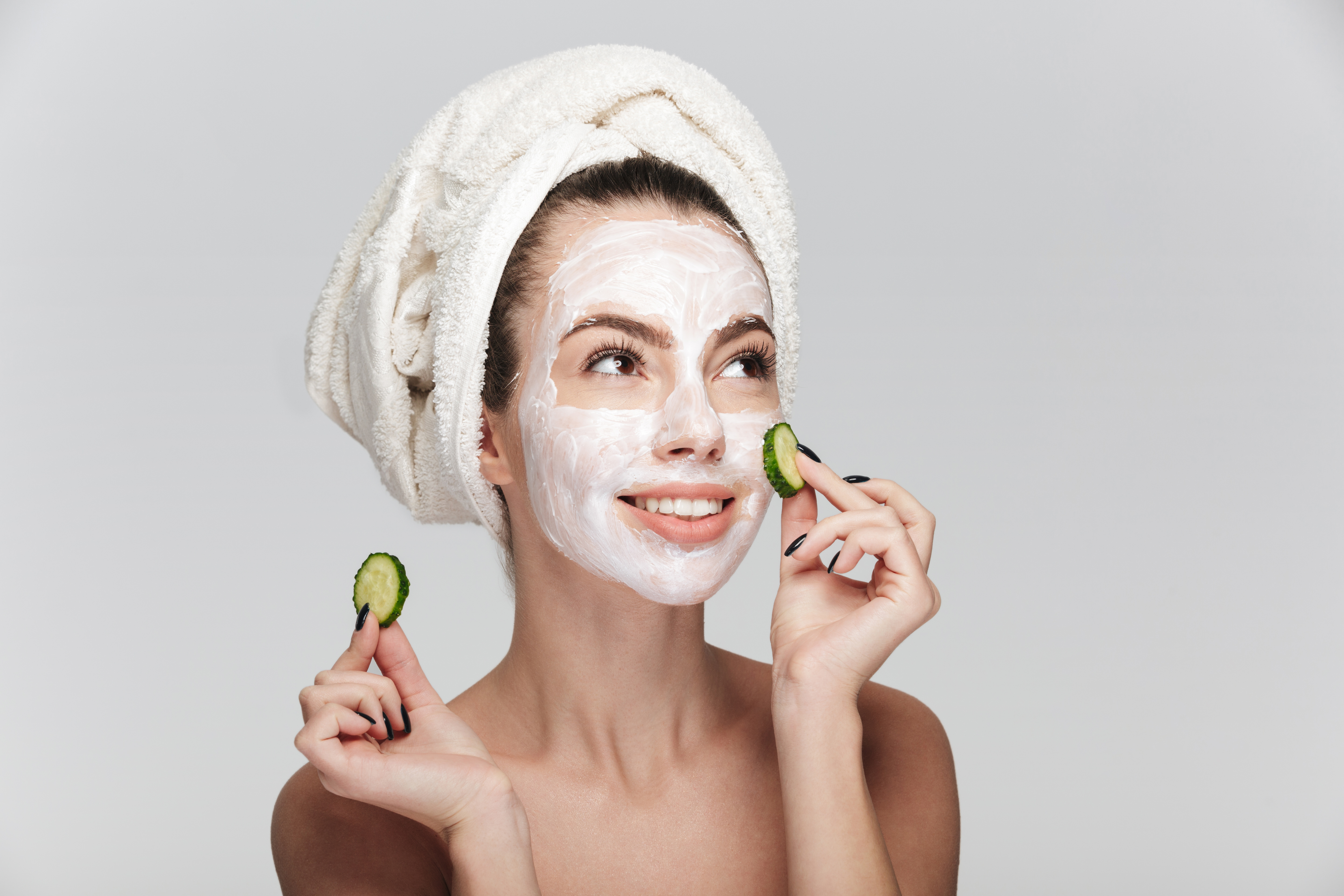 young woman with facial skincare mask and cucumber slices isolated on white