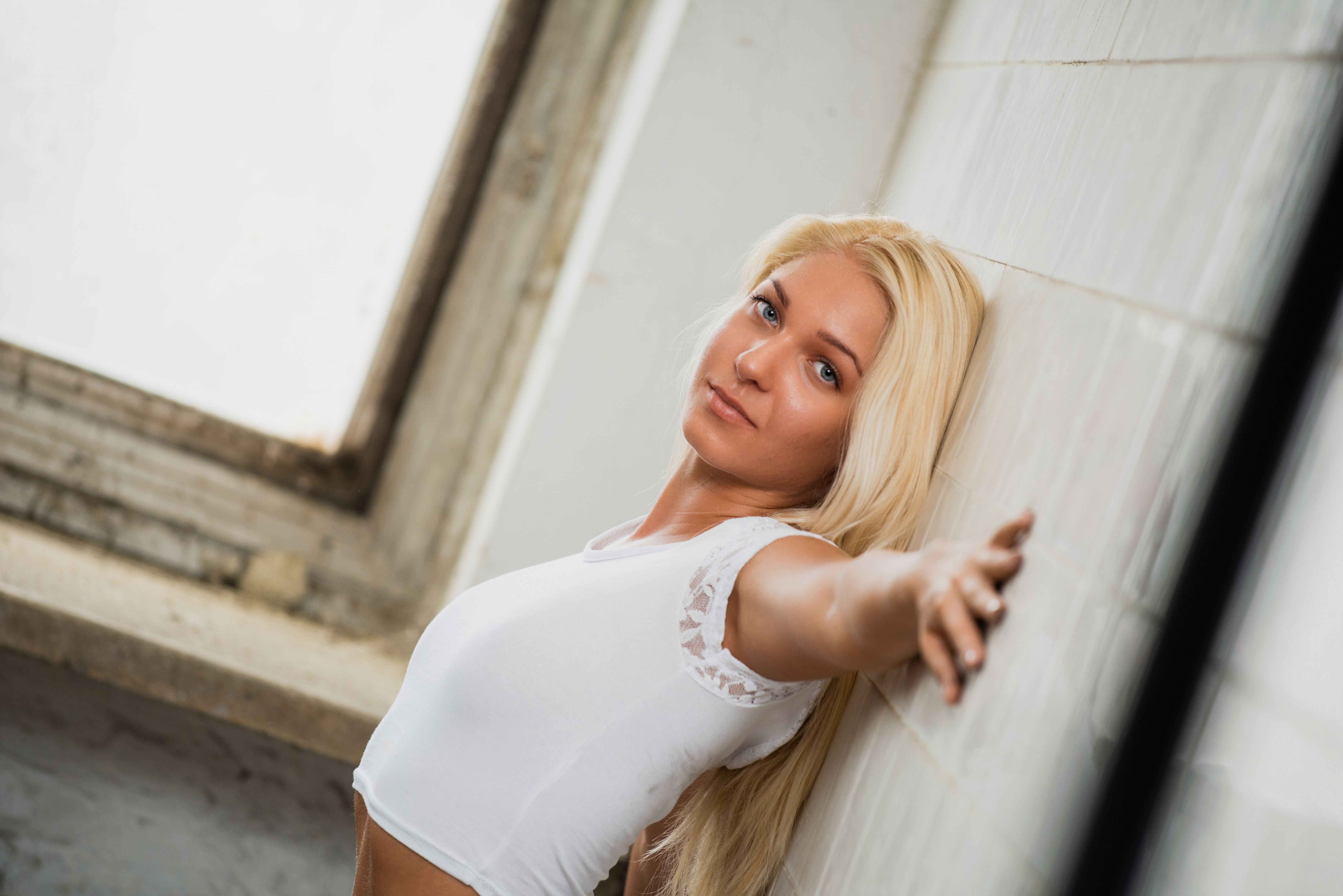 blonde woman leaning against wall in casual outfit