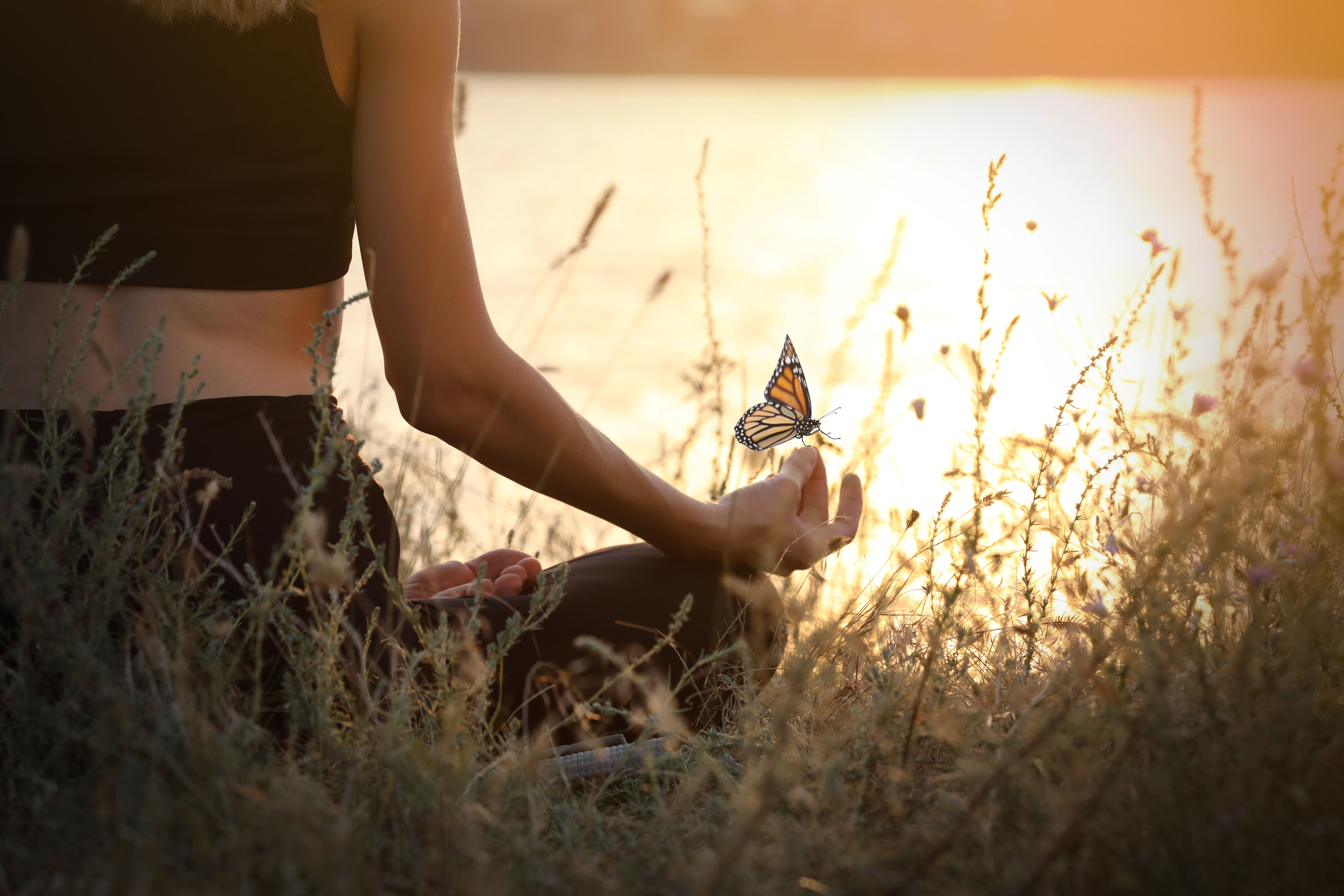 Young woman meditating near river at sunset, closeup