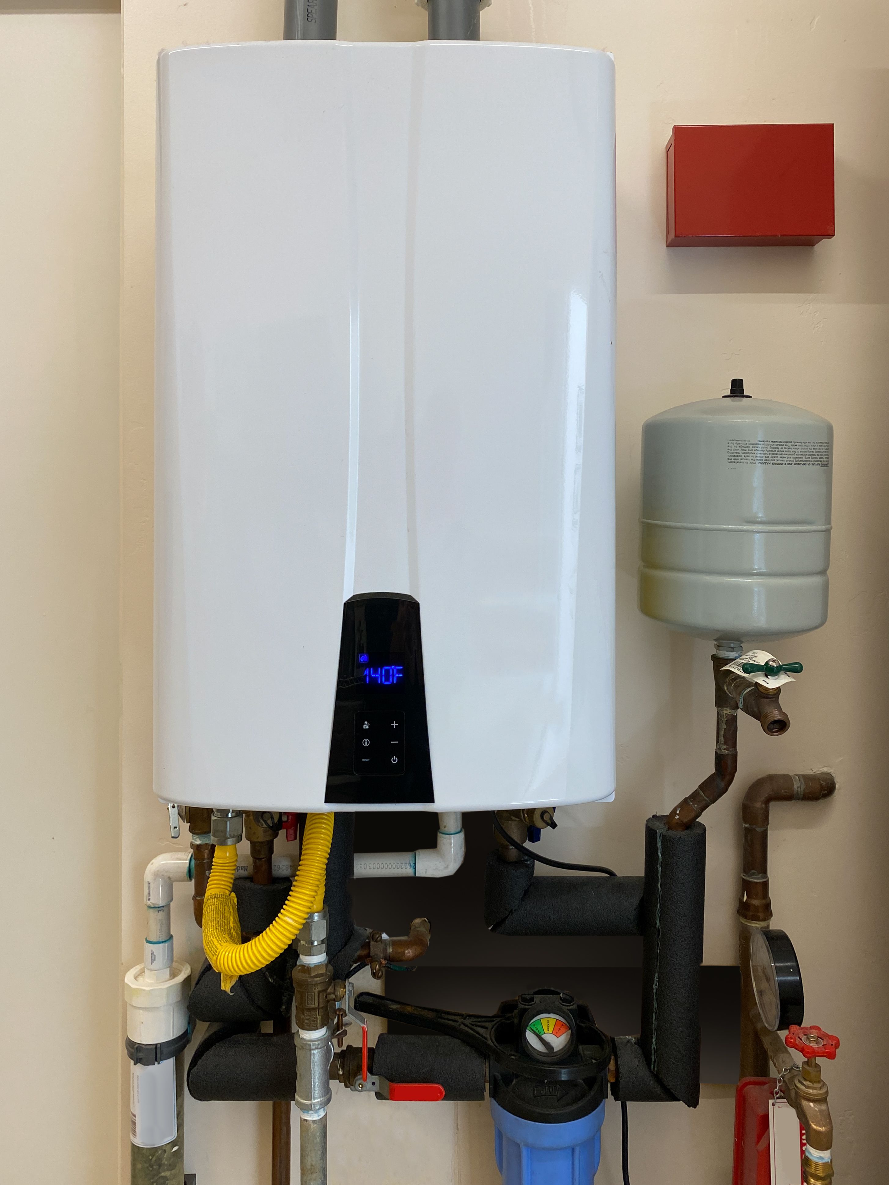 Tankless hot water heater mounted on wall of home Tankless hot water heater mounted on wall of home