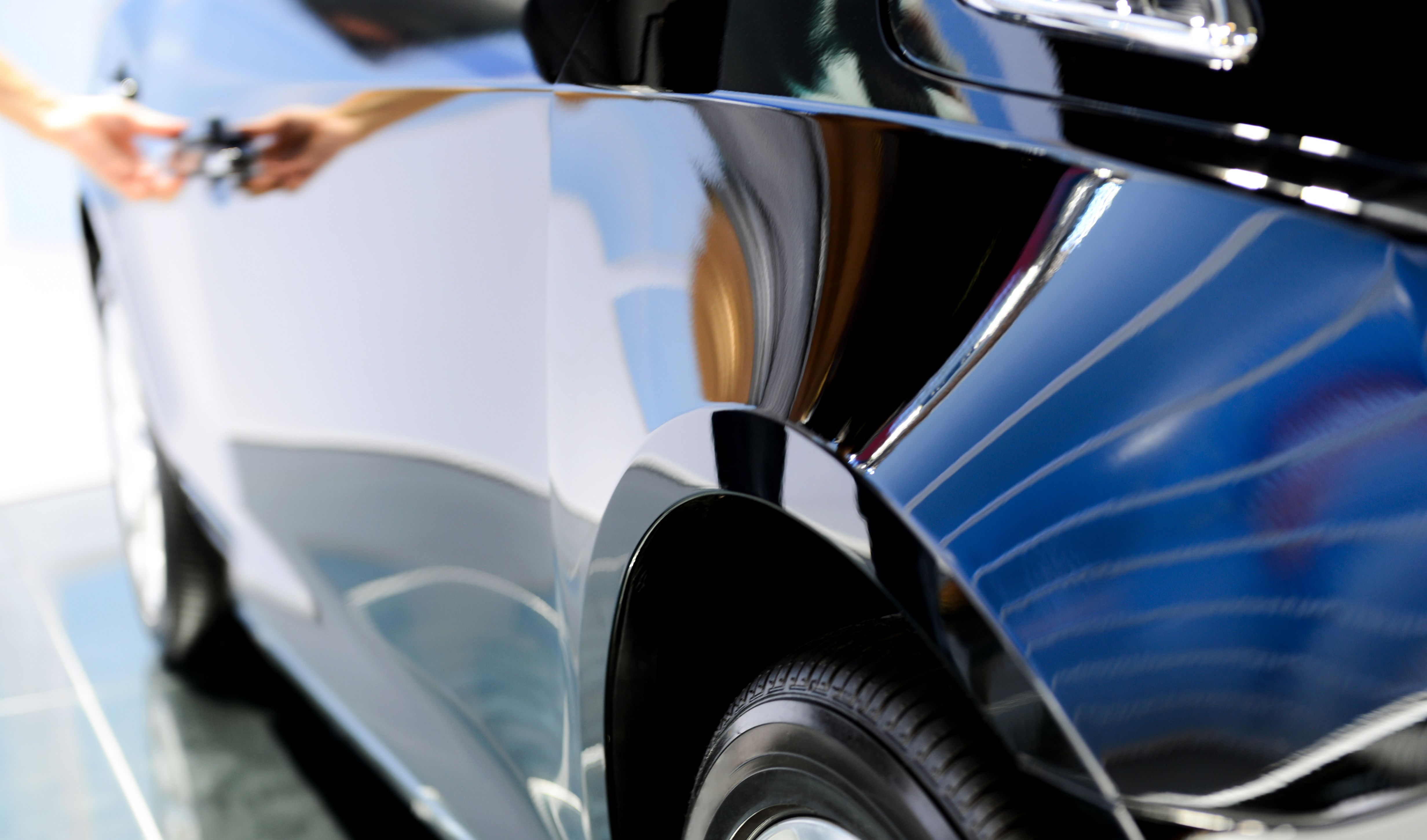 Mano humana abriendo la puerta de un coche de lujo